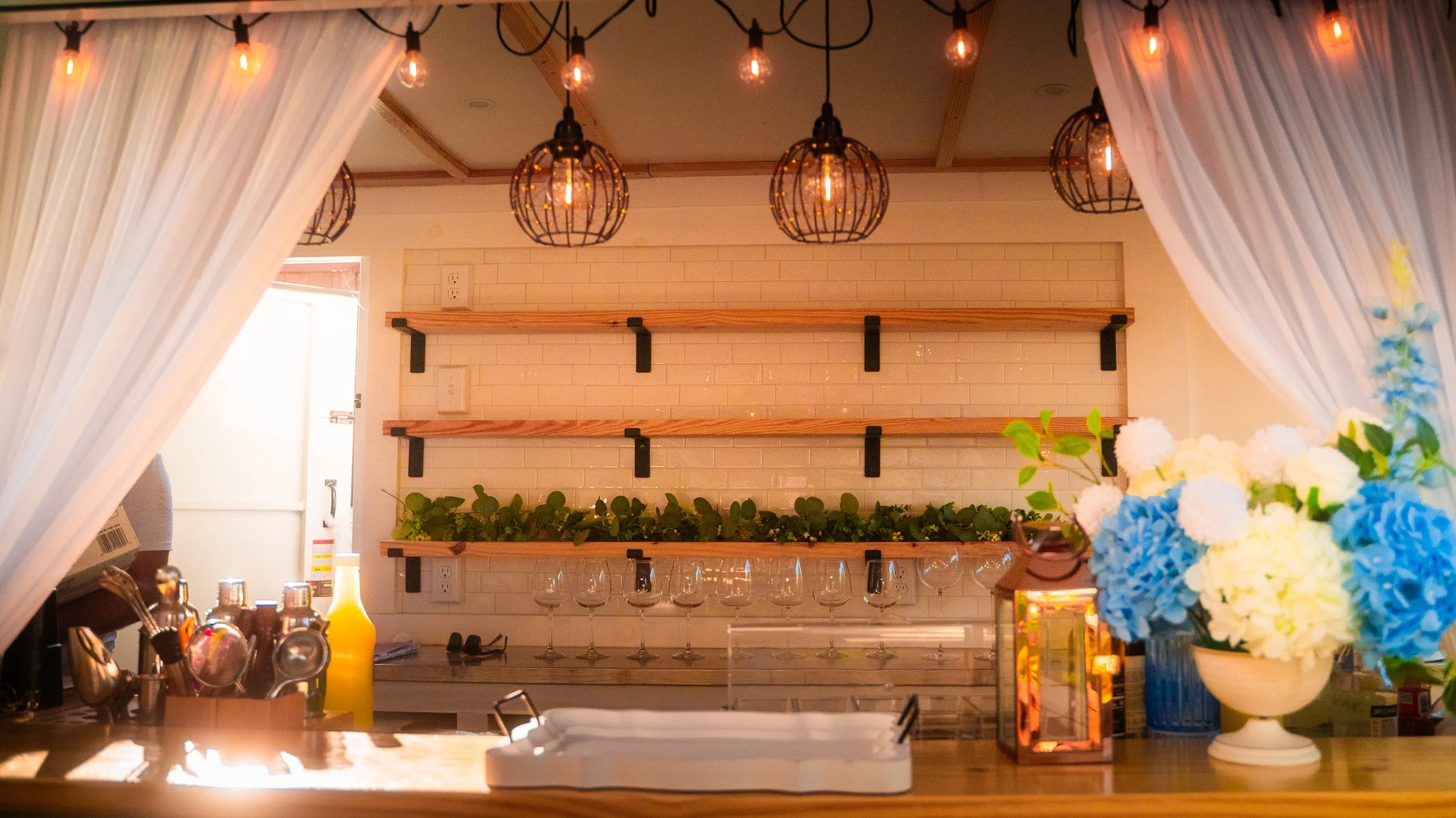 A closeup look of Lumière Bubble Co.'s bar service window with custom floral centerpiece and elegant back shelf, highlighting the aesthetics-forward mobile bar brand.