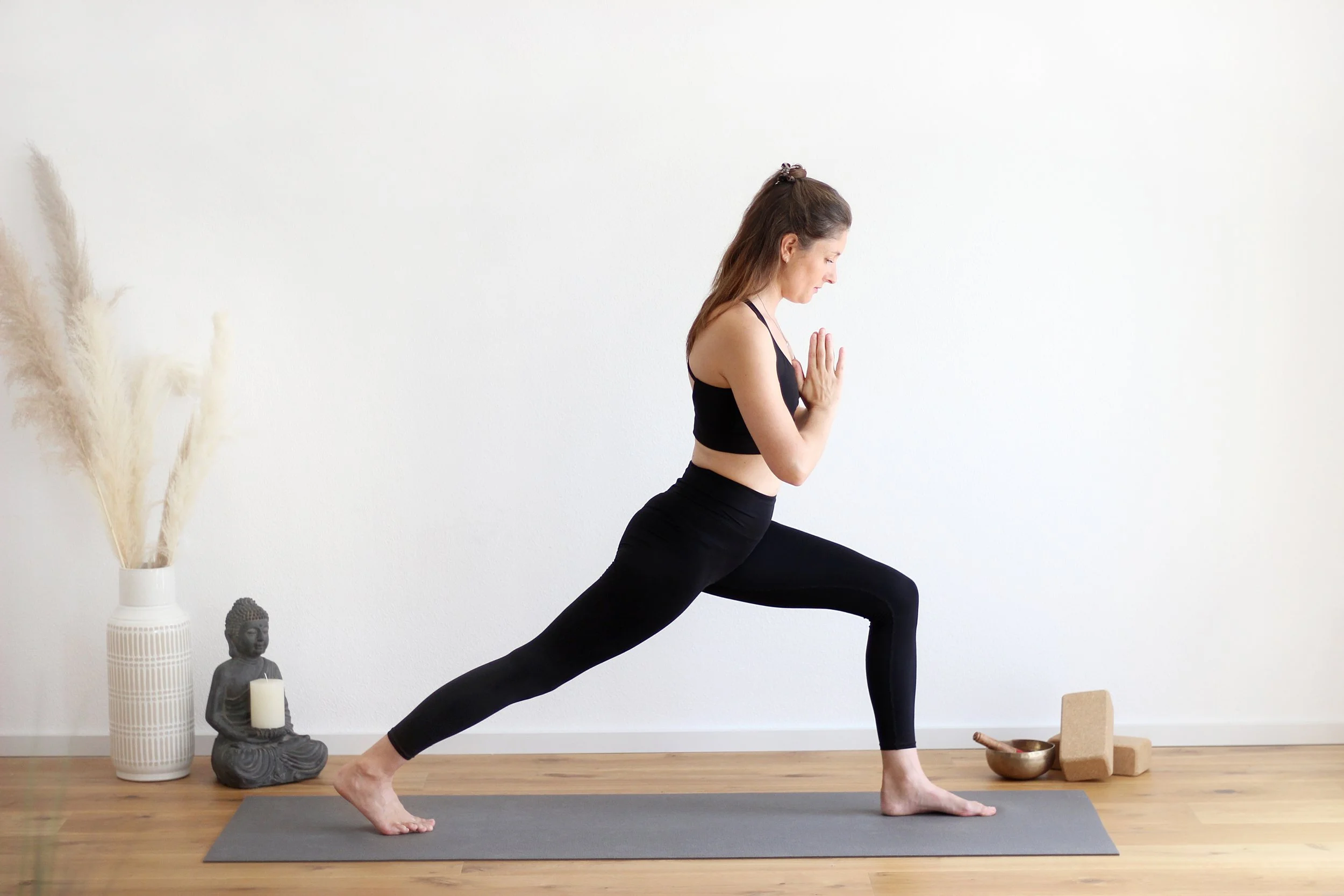 Yogalehrerin in der Krieger-II-Haltung in einem ruhigen Yogaraum in Kaufbeuren.