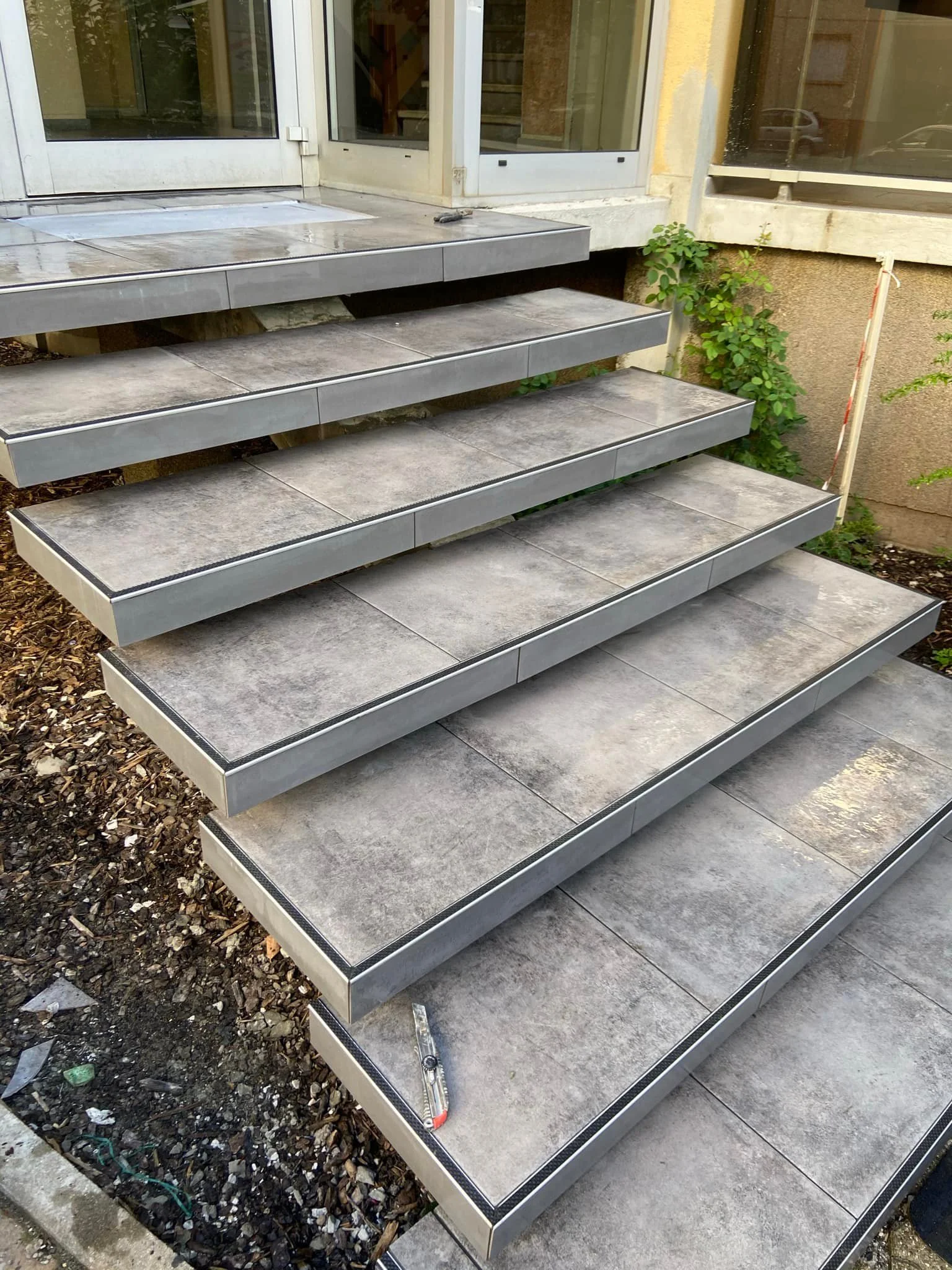 Escalier en béton et métal menant à une entrée avec porte en verre
