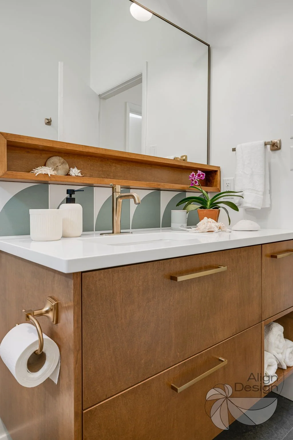 Mid-century modern bathroom with green and white tile, wood vanity, and brass fixtures in a small remodeled space.