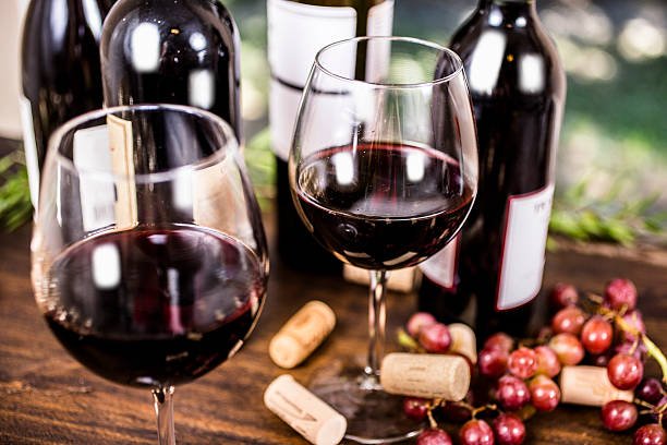 red wine in glass with corks and bottles.jpg