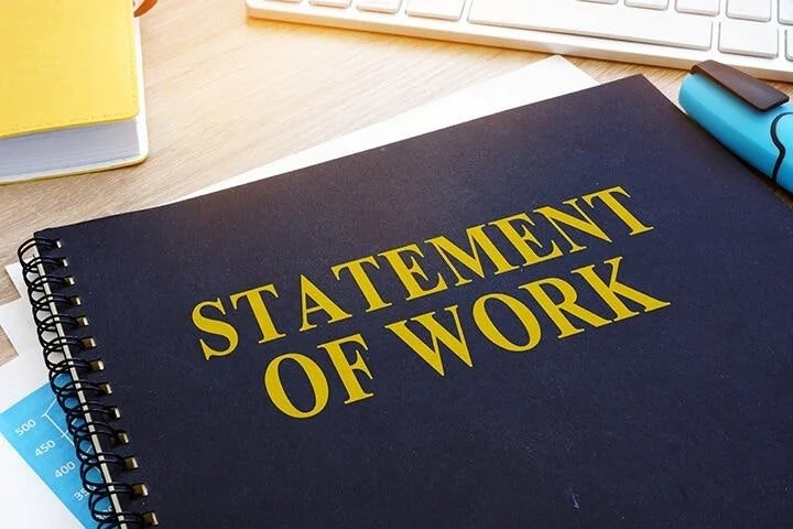 A notebook titled 'Statement of Work' on a desk, with a keyboard and office supplies nearby.