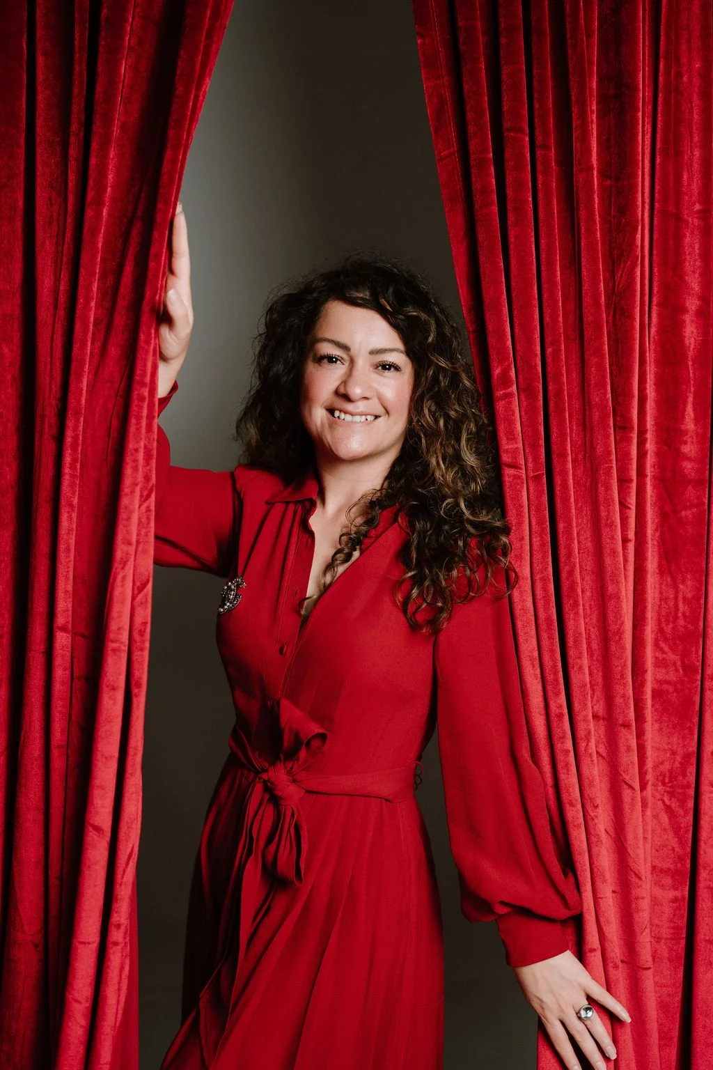 Cynthia Platero, Executive Coach in between red velvet curtains.