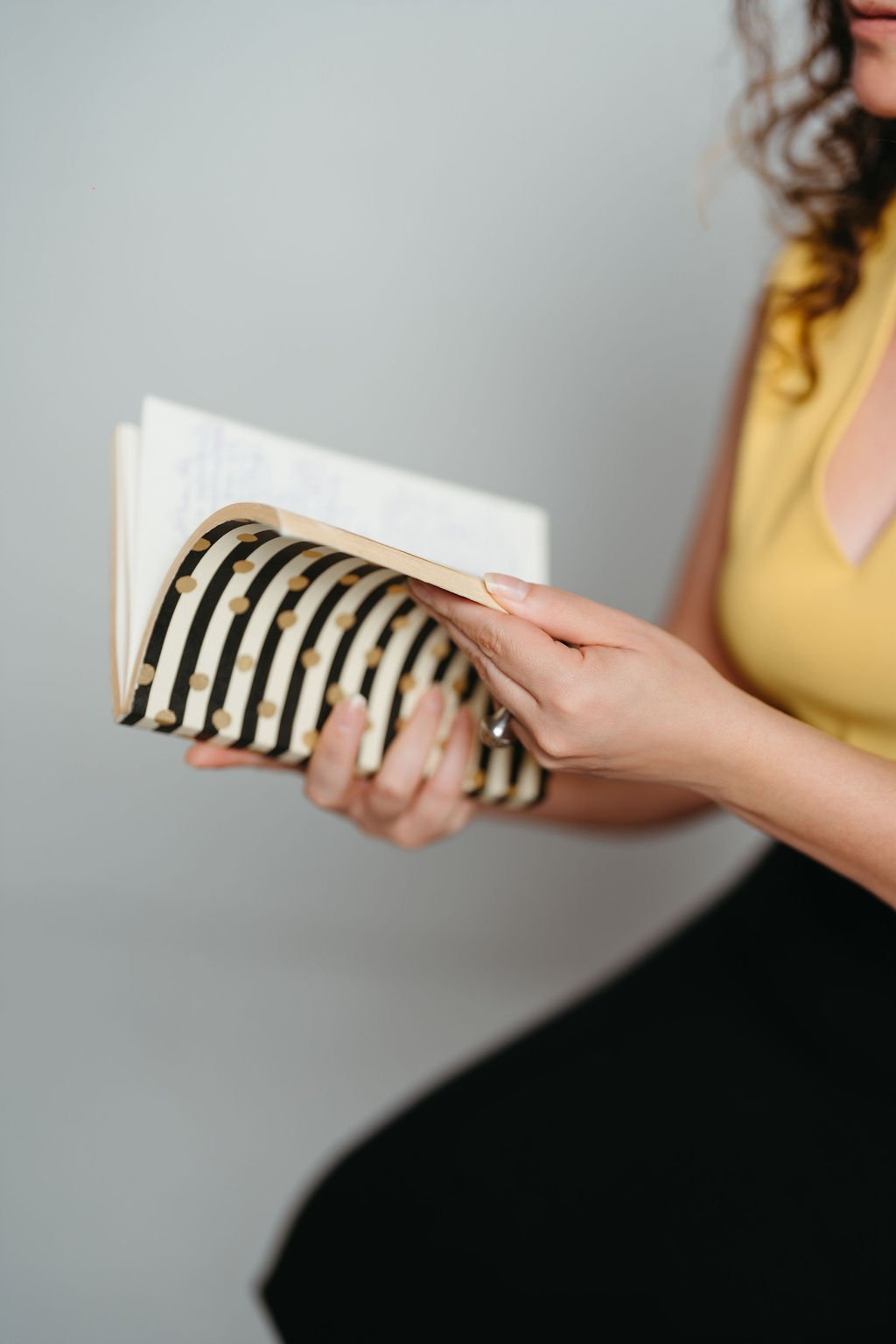 Cynthia Platero, Executive Coach holding a black and white striped notebook.