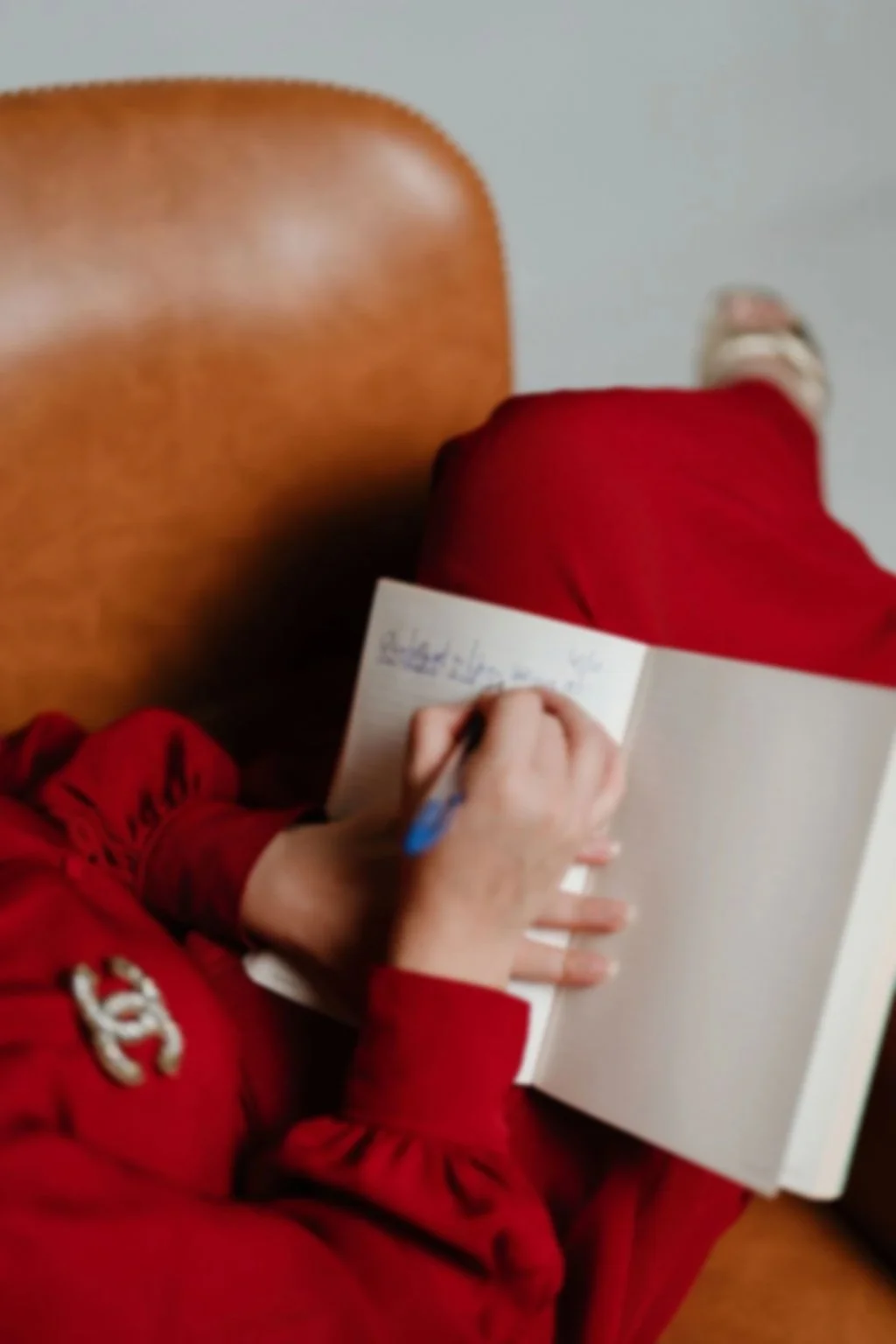 Cynthia Platero, executive coach for high-achieving creative women is sitting and writing in a notebook. The image is captured from above.