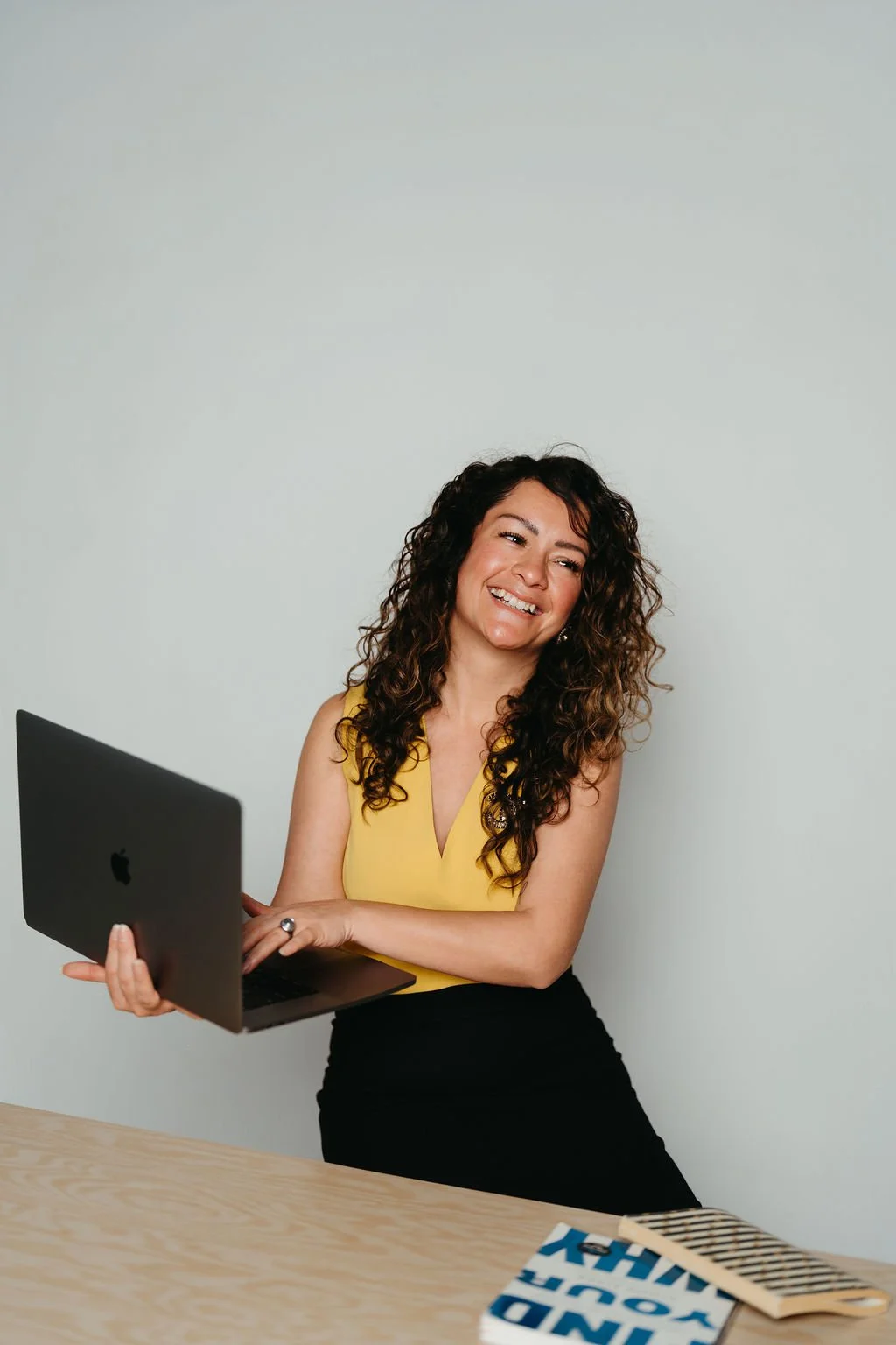 Cynthia Platero, executive coach for high-achieving creative women, holding a laptop.