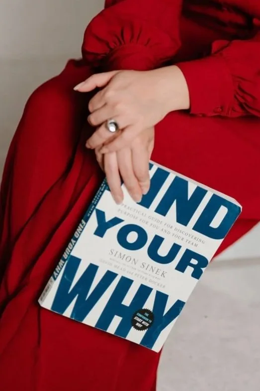 Cynthia Platero, executive coach for high-achieving creative women holding a book titled 'Find Your Why' by Simon Sinek.