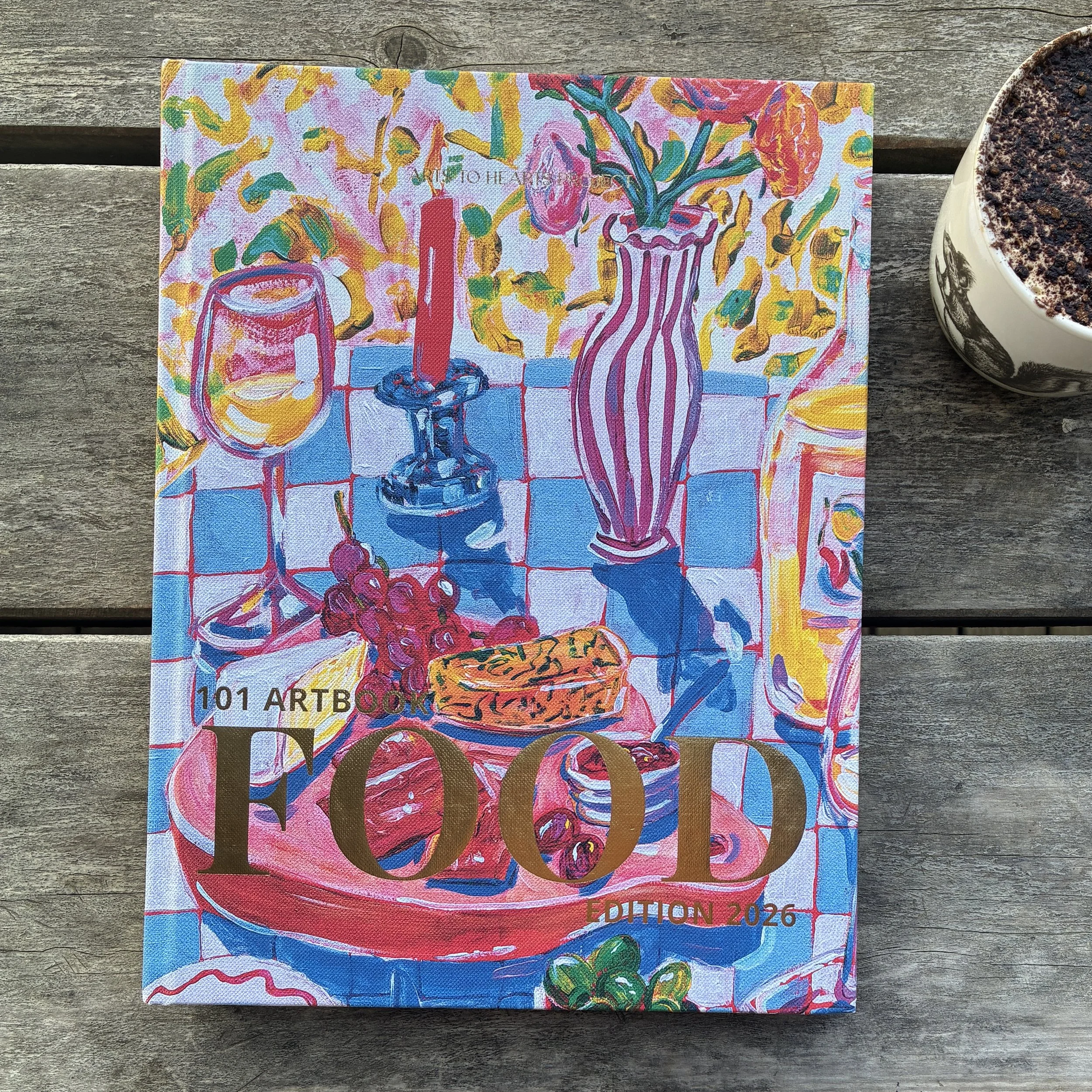 Colorful art piece featuring various objects, including a wine glass, a candle, a vase with flowers, grapes, and text indicating it is from the 101 Art Book, edition 2026, on a wooden surface.