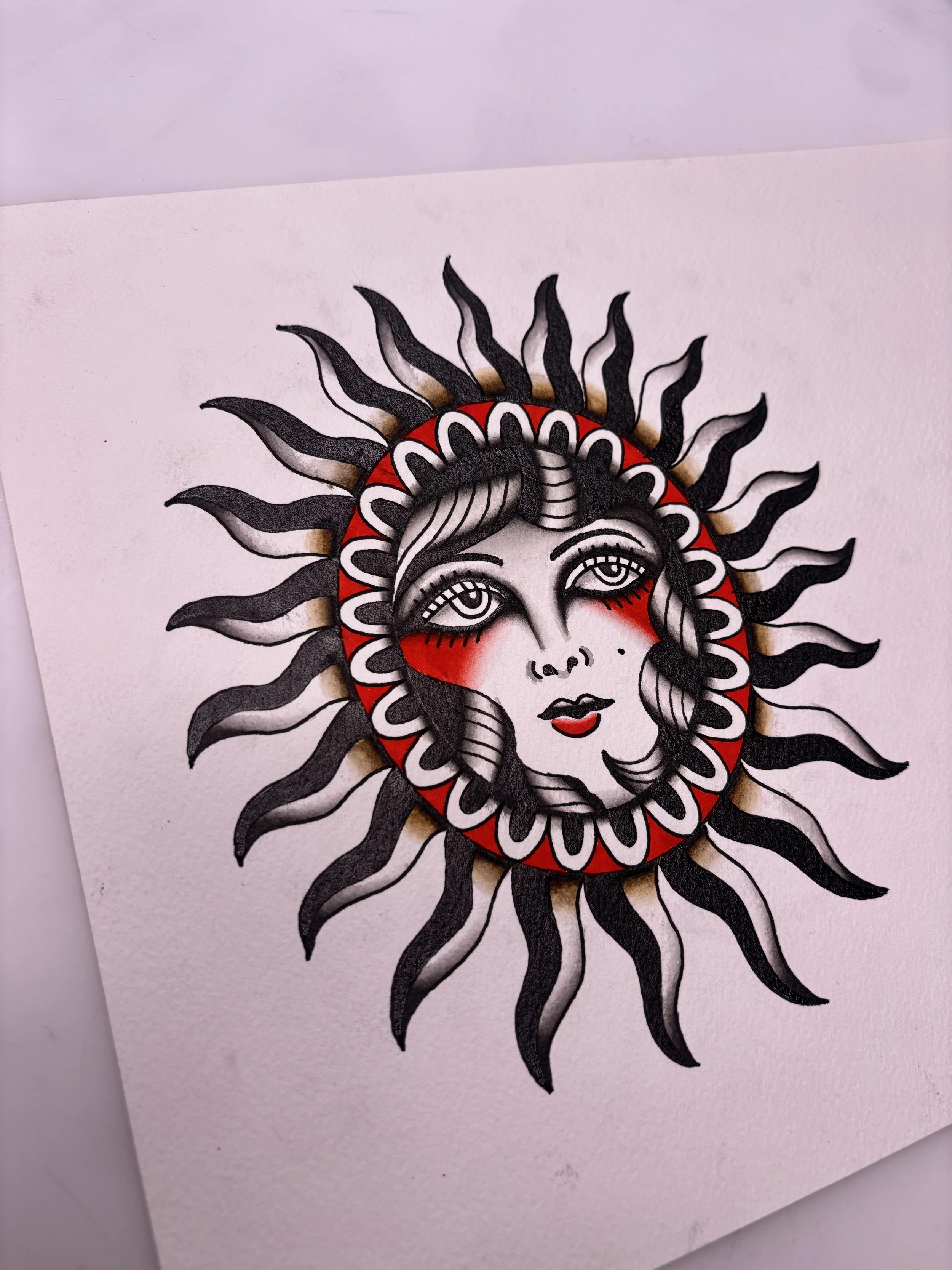 A tattoo design of a woman's face inside a stylized sun with black rays, red and black details, and intricate line work.