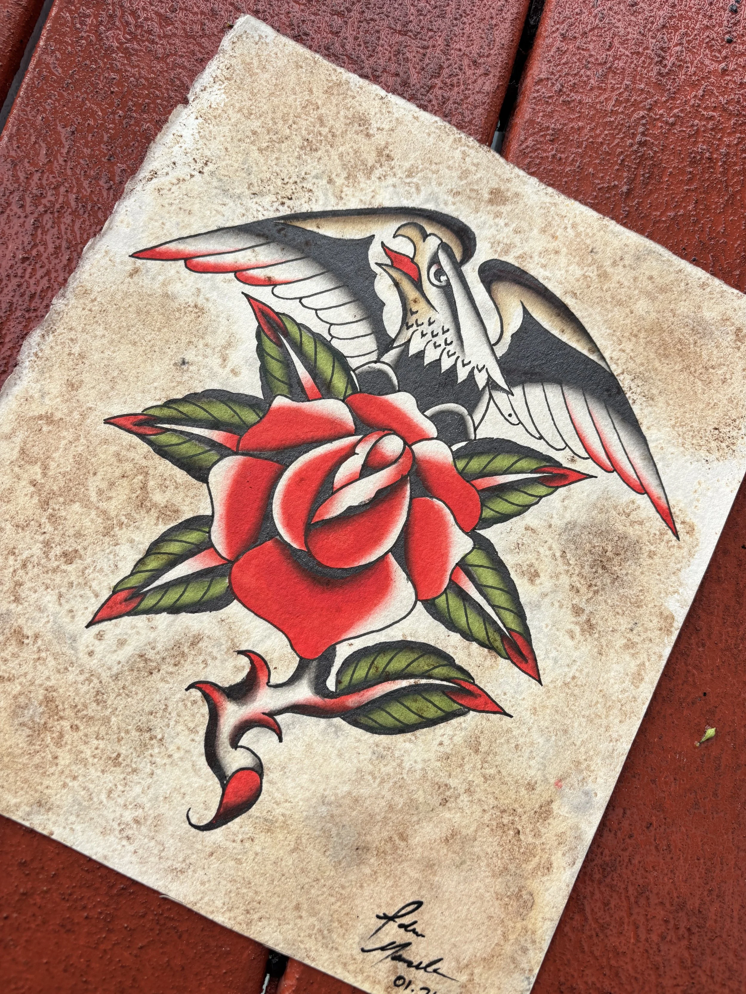 Tattoo-style illustration of a red rose with green leaves and a swallow bird flying above it. The drawing has bold black outlines and shading, and there is a signature with a date at the bottom.