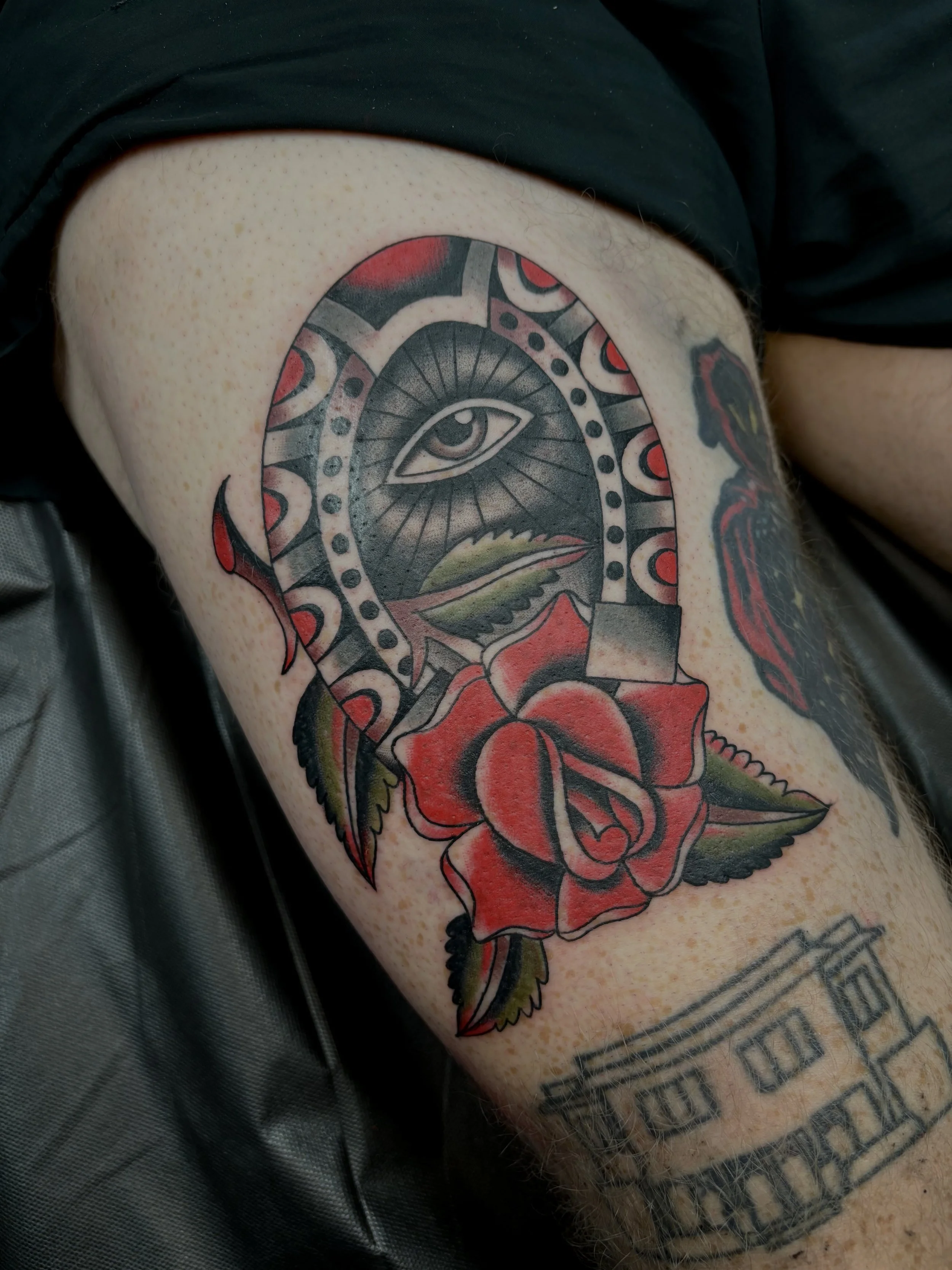 Tattoo of a rose with a snake and an eye on the arm.