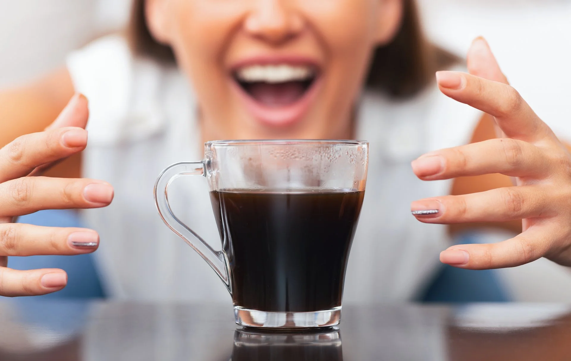 Woman grabbing for a warm cup of coffee with two hands.