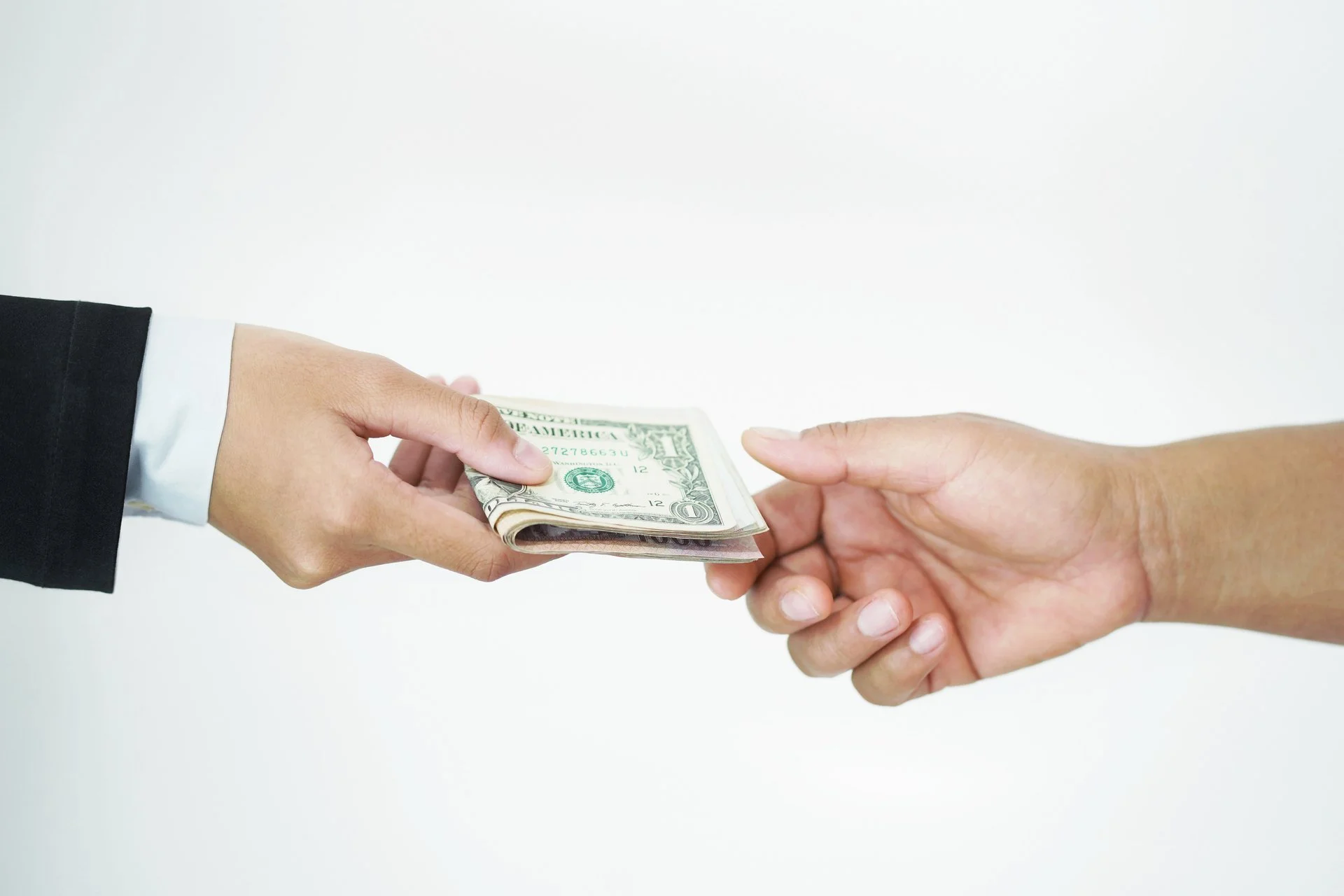 One hand passing money to another person's hand.