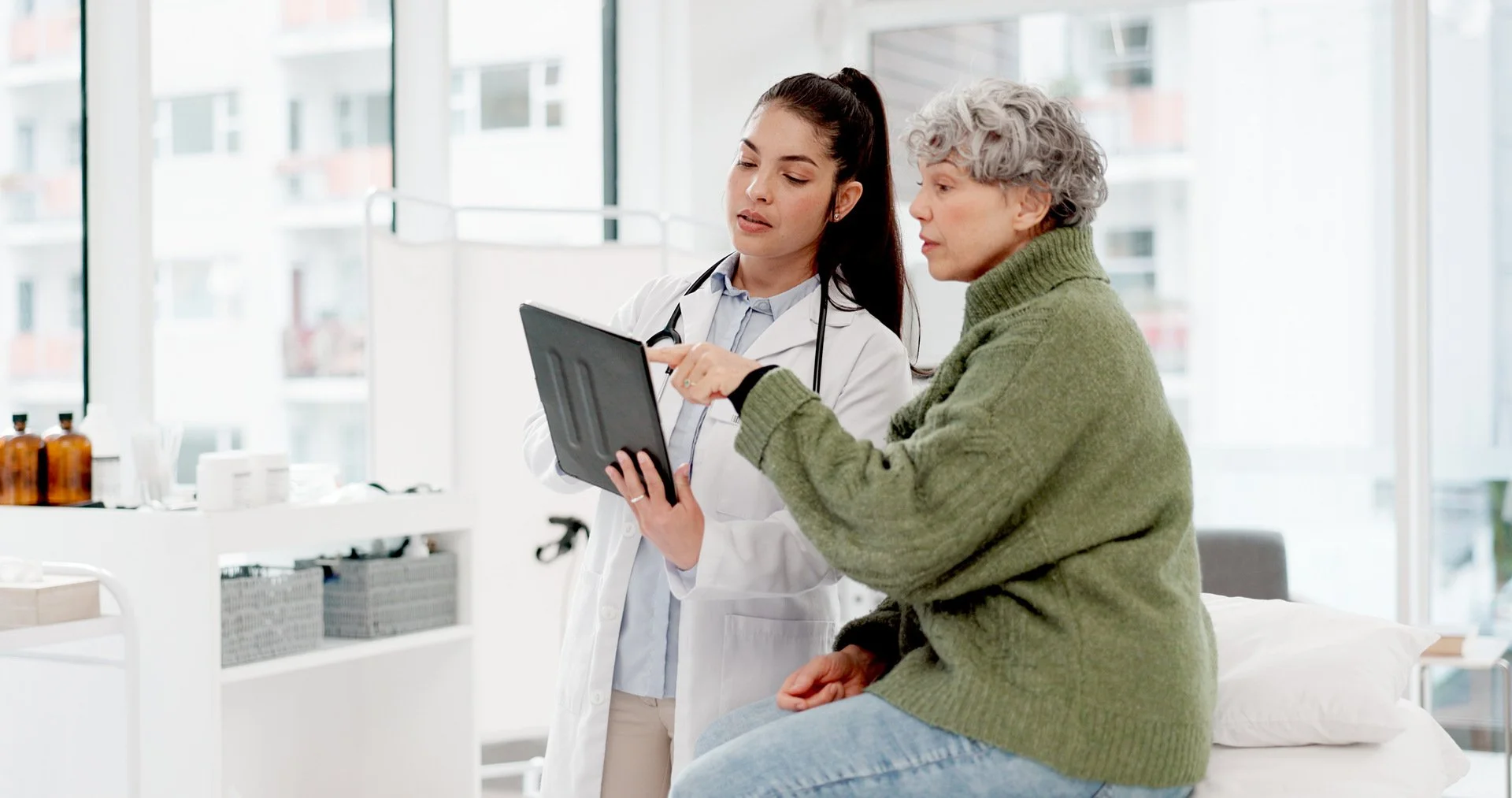 Doctor and patient looking at and discussing what is on the screen of a tablet device.