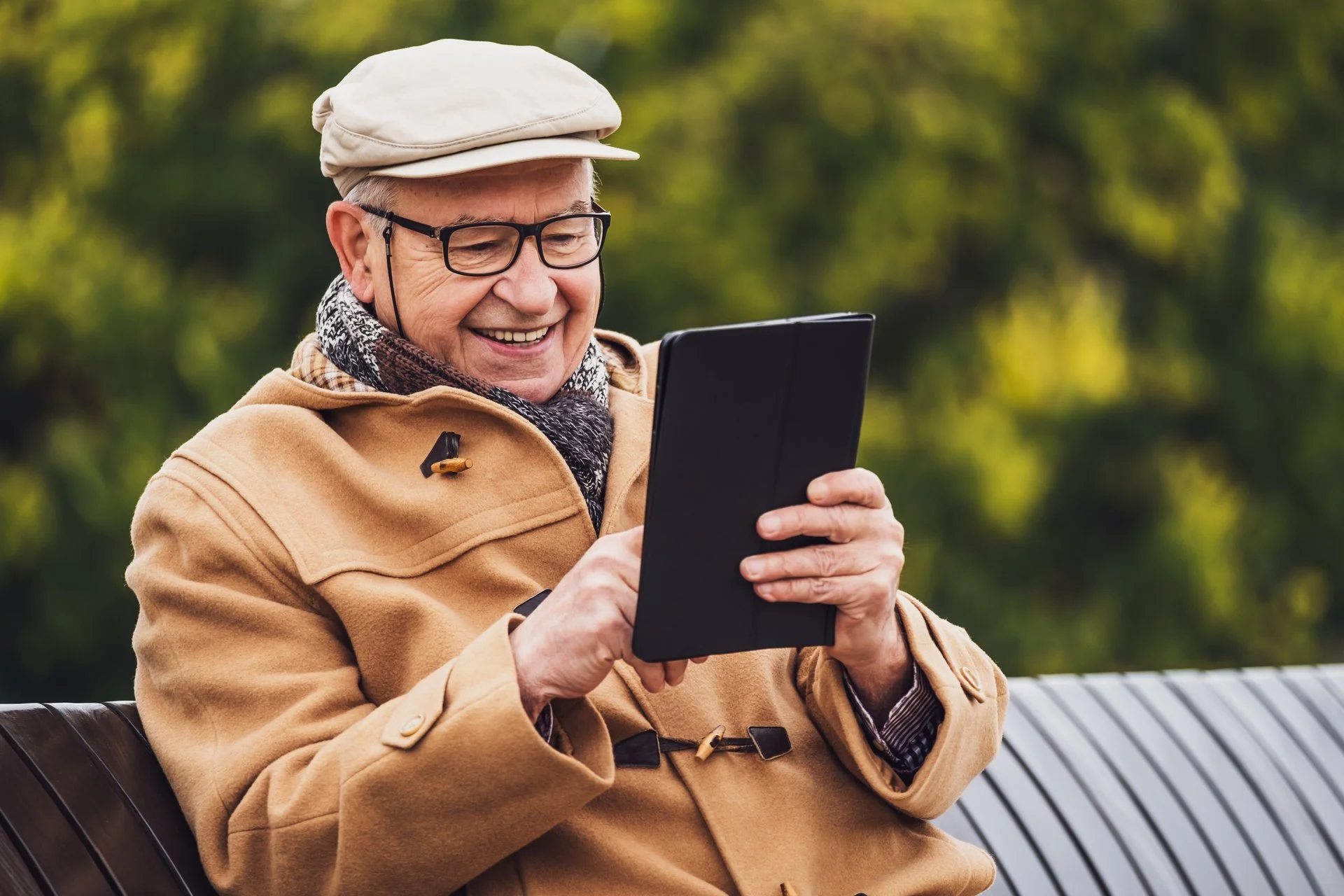A man sitting on a bench and reading a tablet.