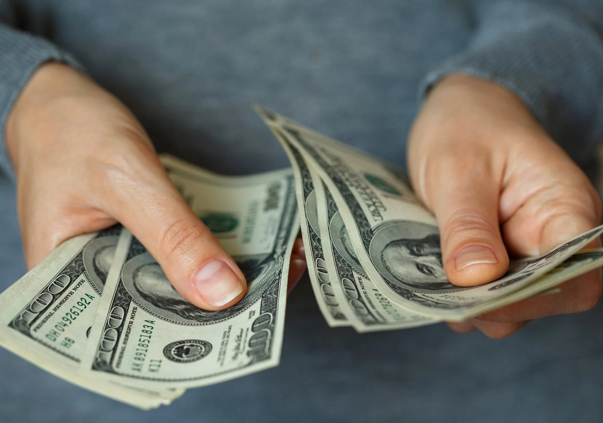 Person counting money with both hands but no face visible.