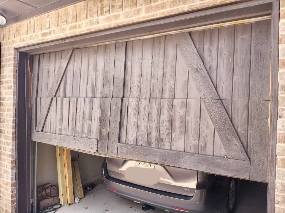 Damaged wood barn-style garage door before repair