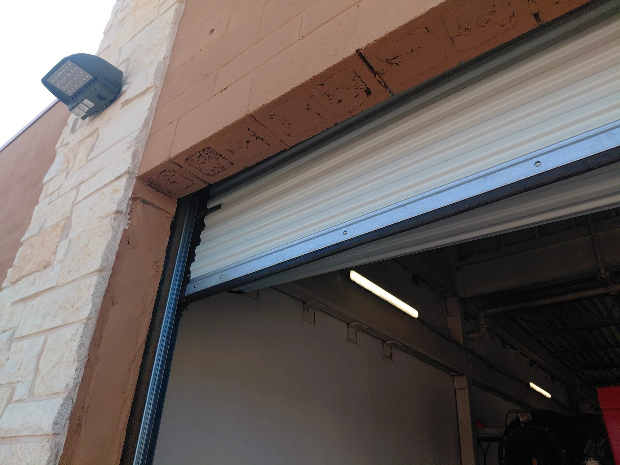 Newly installed commercial roll-up door on a stone storefront in the Dallas–Fort Worth area