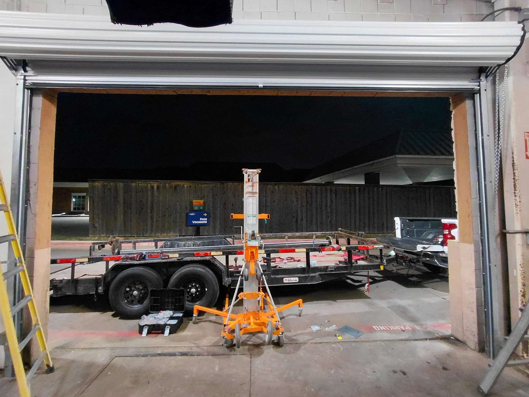 New roll-up door coil raised on a lift for installation in a commercial bay