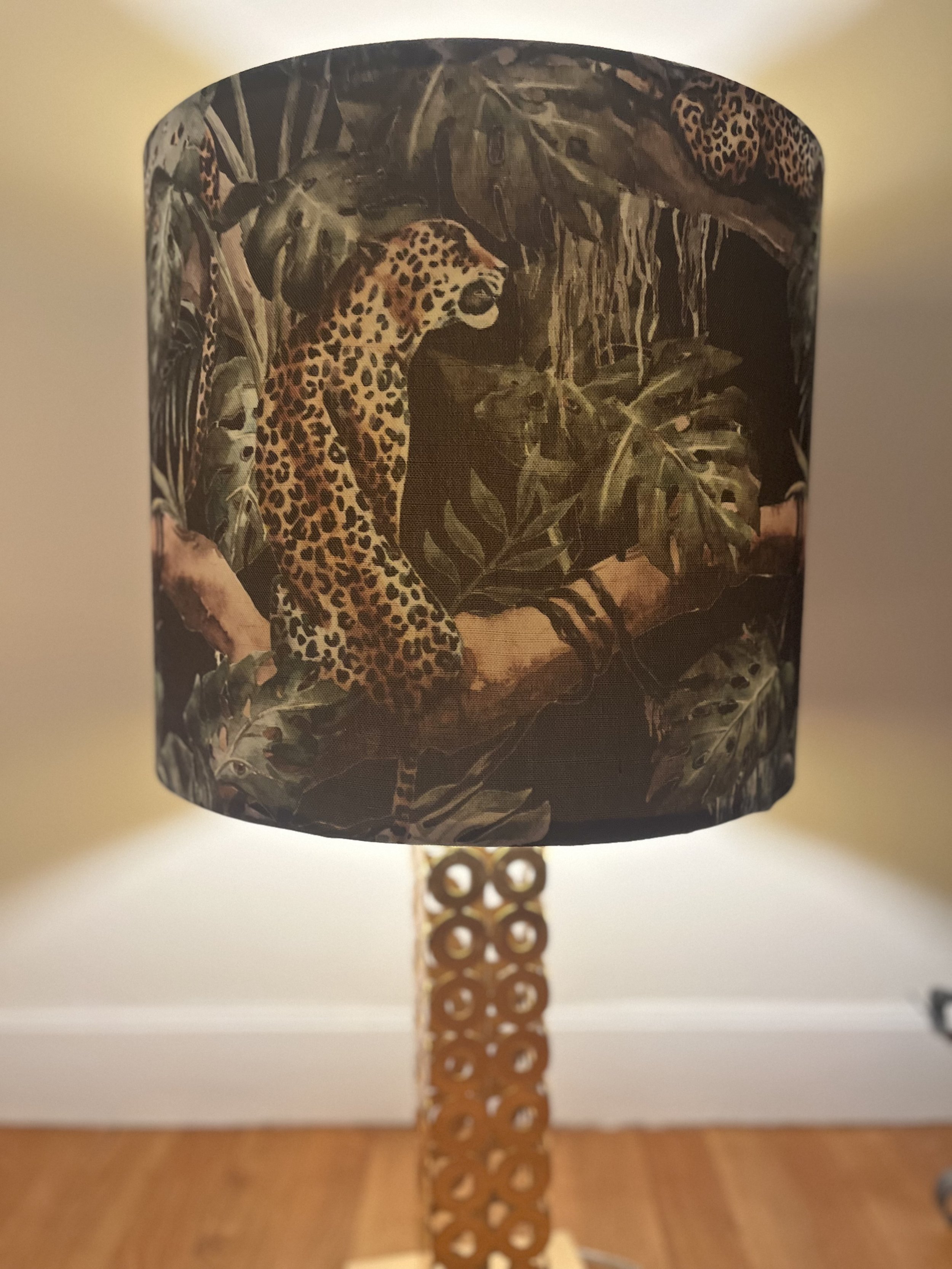 Lamp with a decorative shade featuring leopards and jungle foliage.