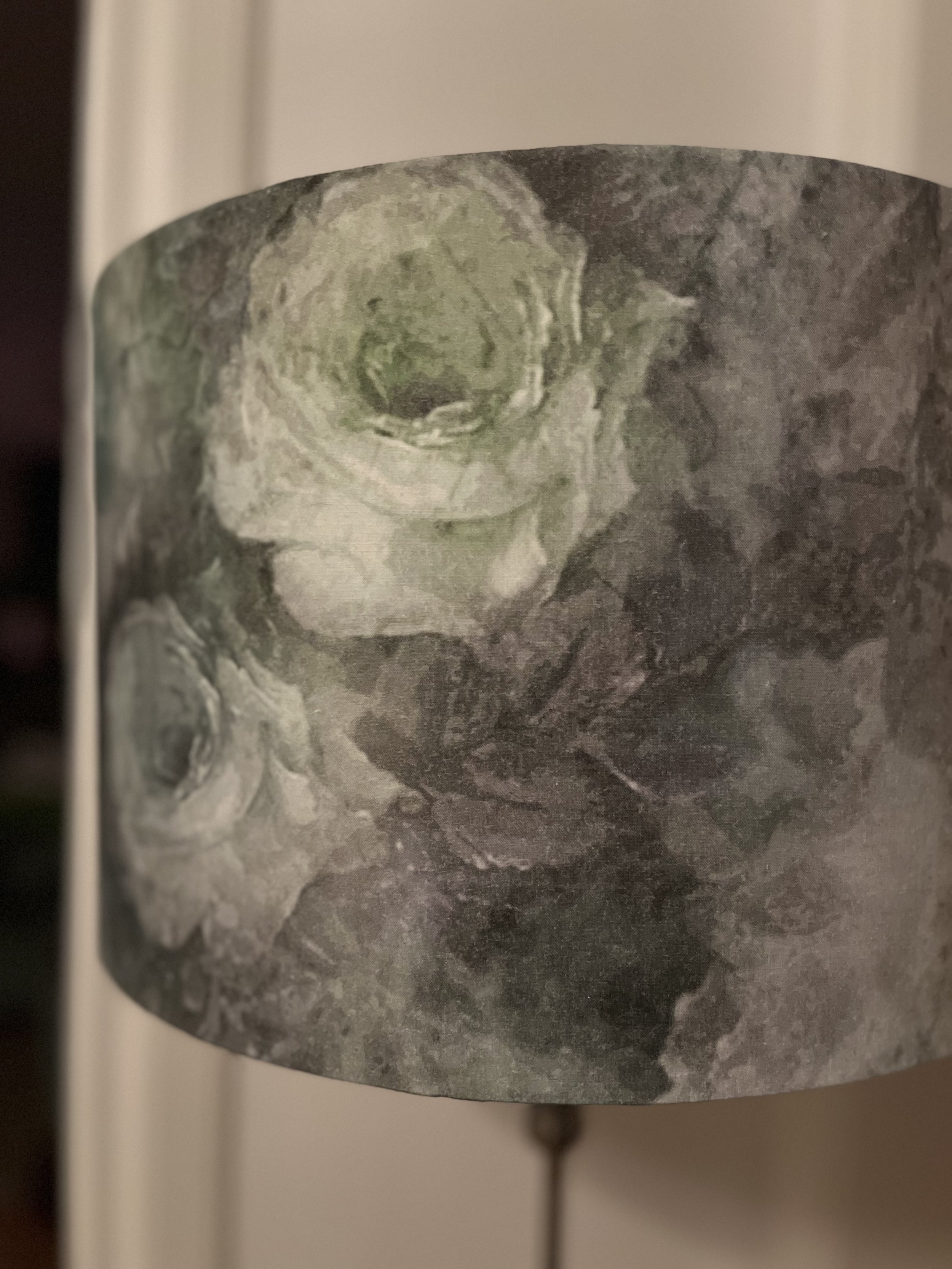 Close-up of a floral pattern on a lamp shade with muted green and gray tones.