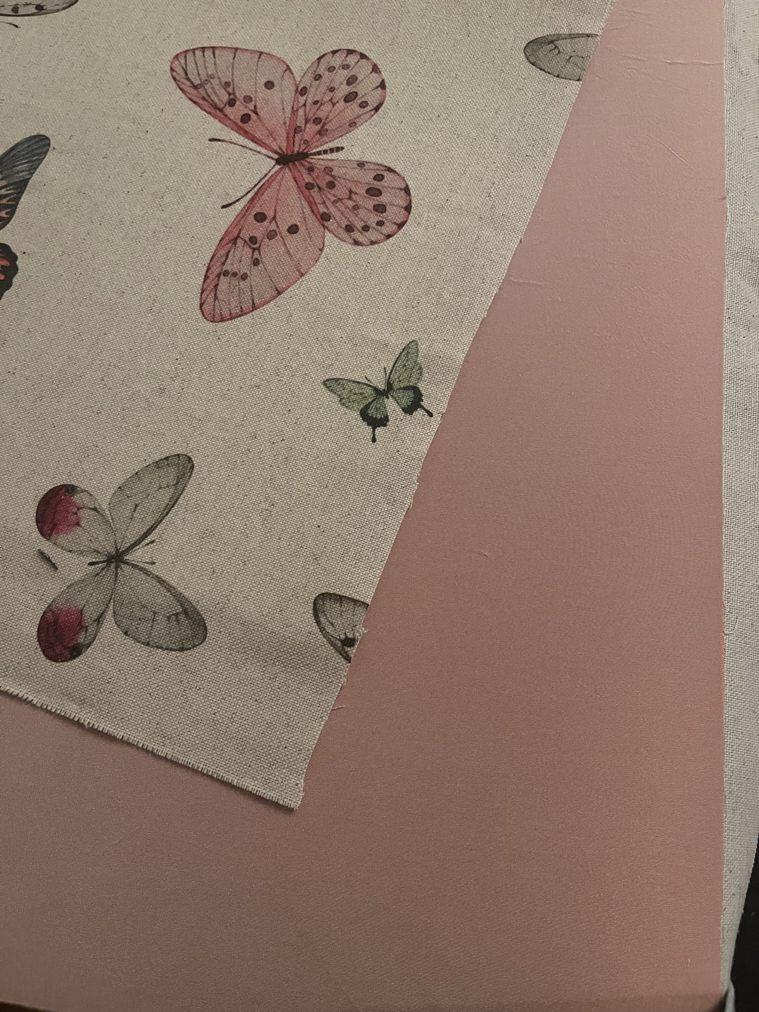 Fabric with butterfly pattern next to pink material.