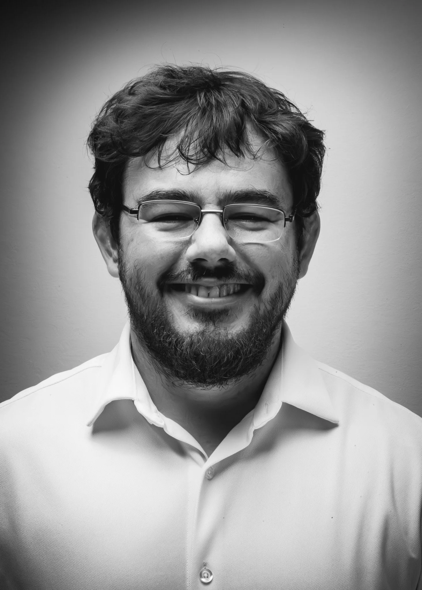 Porträt eines lächelnden Mannes mit Brille und Bart, schwarz-weiß