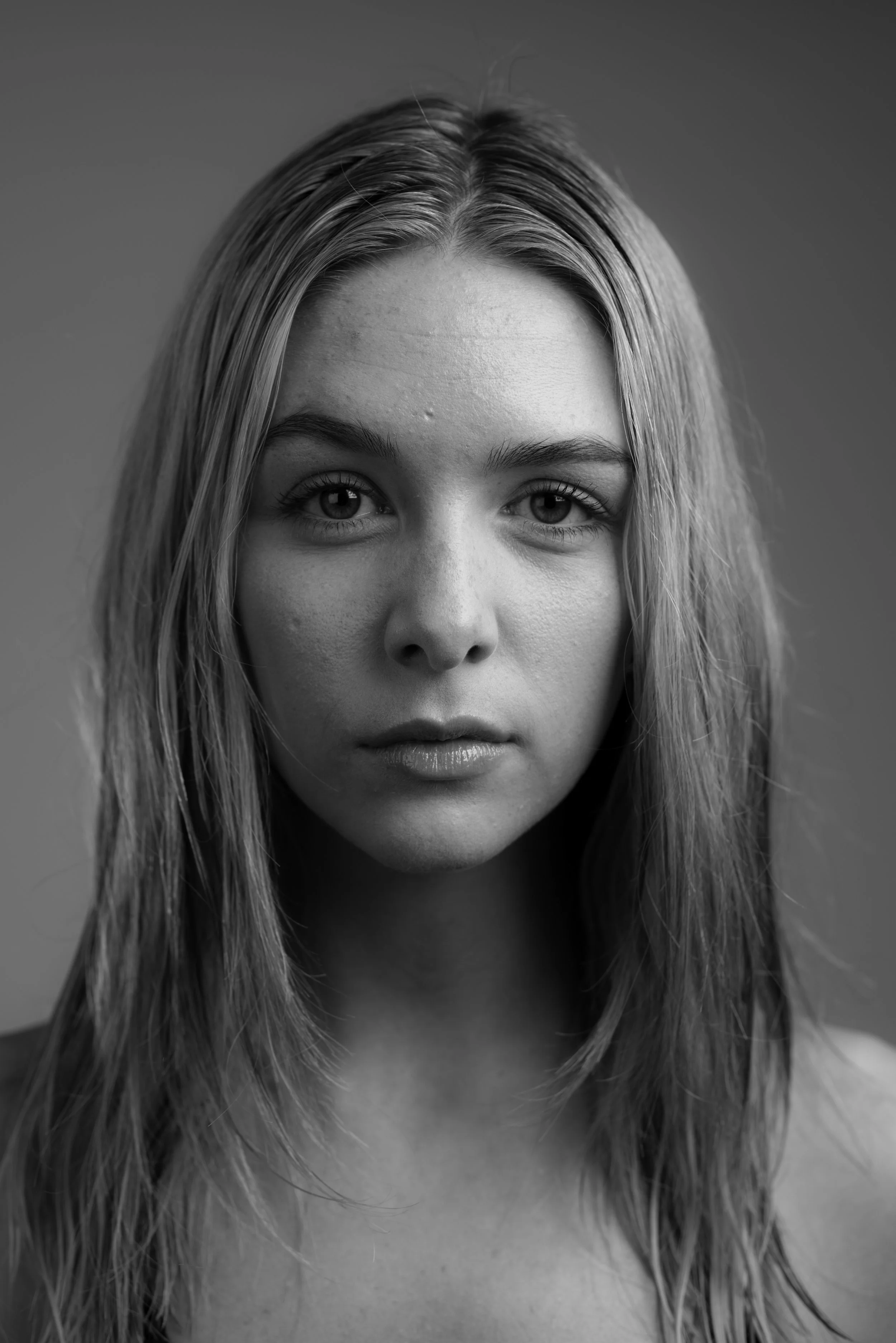 Black and white portrait of a young woman with straight, shoulder-length hair, looking directly at the camera with a neutral expression.