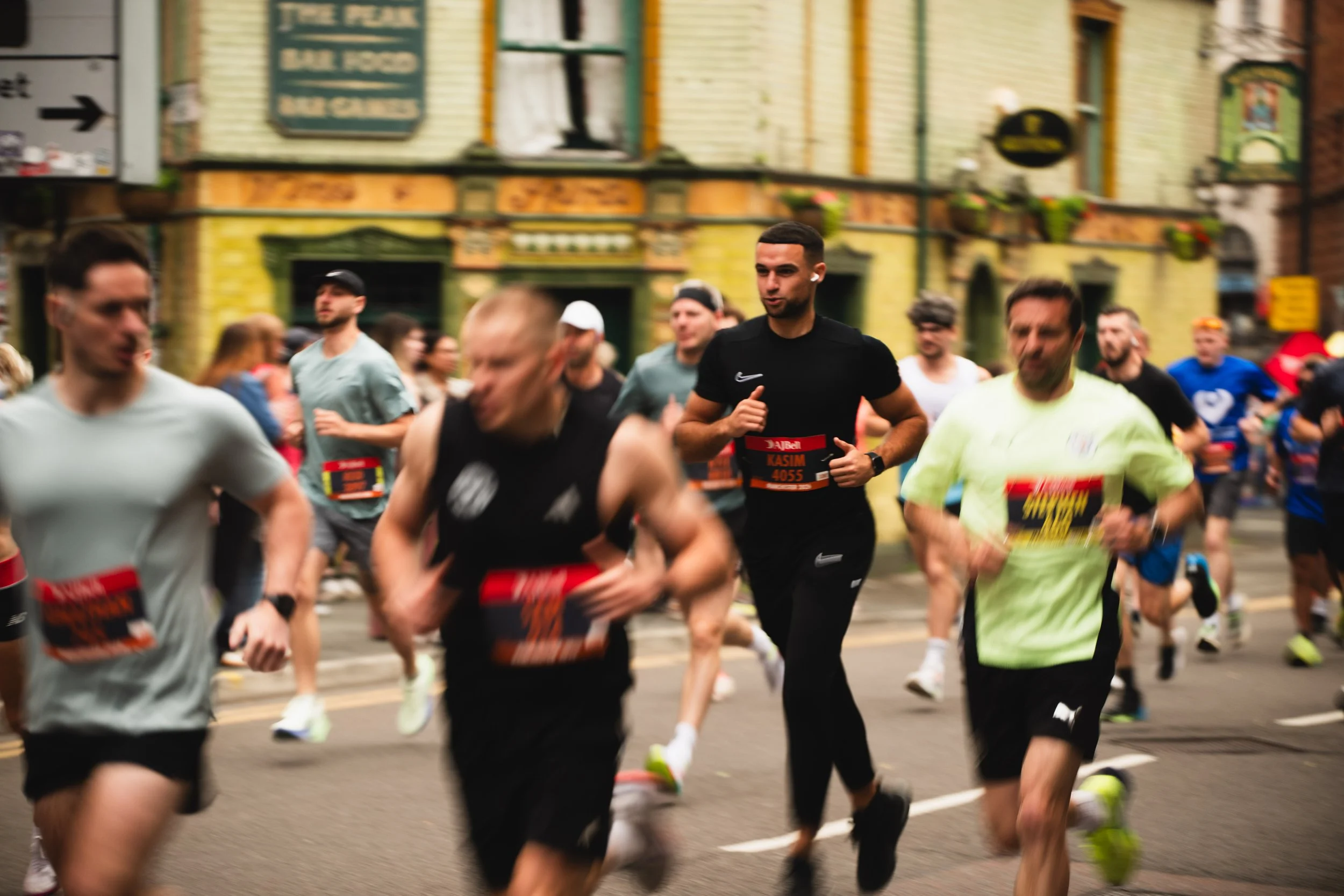 A group of people running in a race on a city street, with historic buildings in the background.