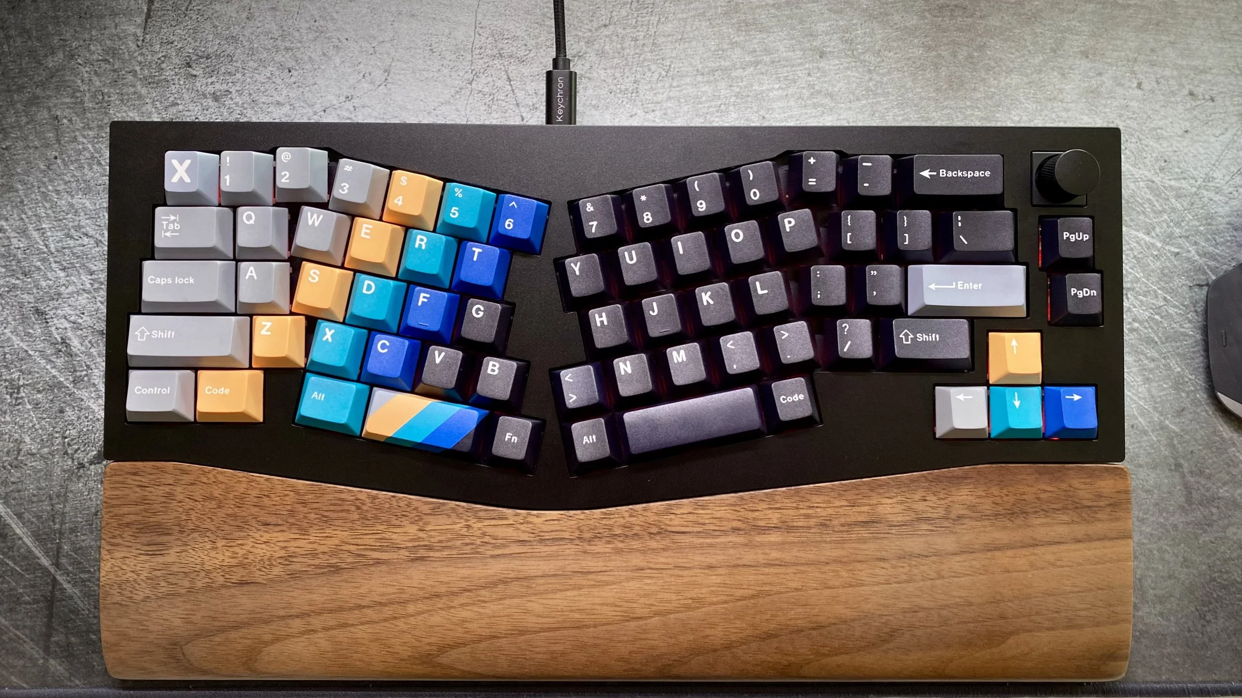 Split keyboard with colorful keycaps and wooden wrist rest.