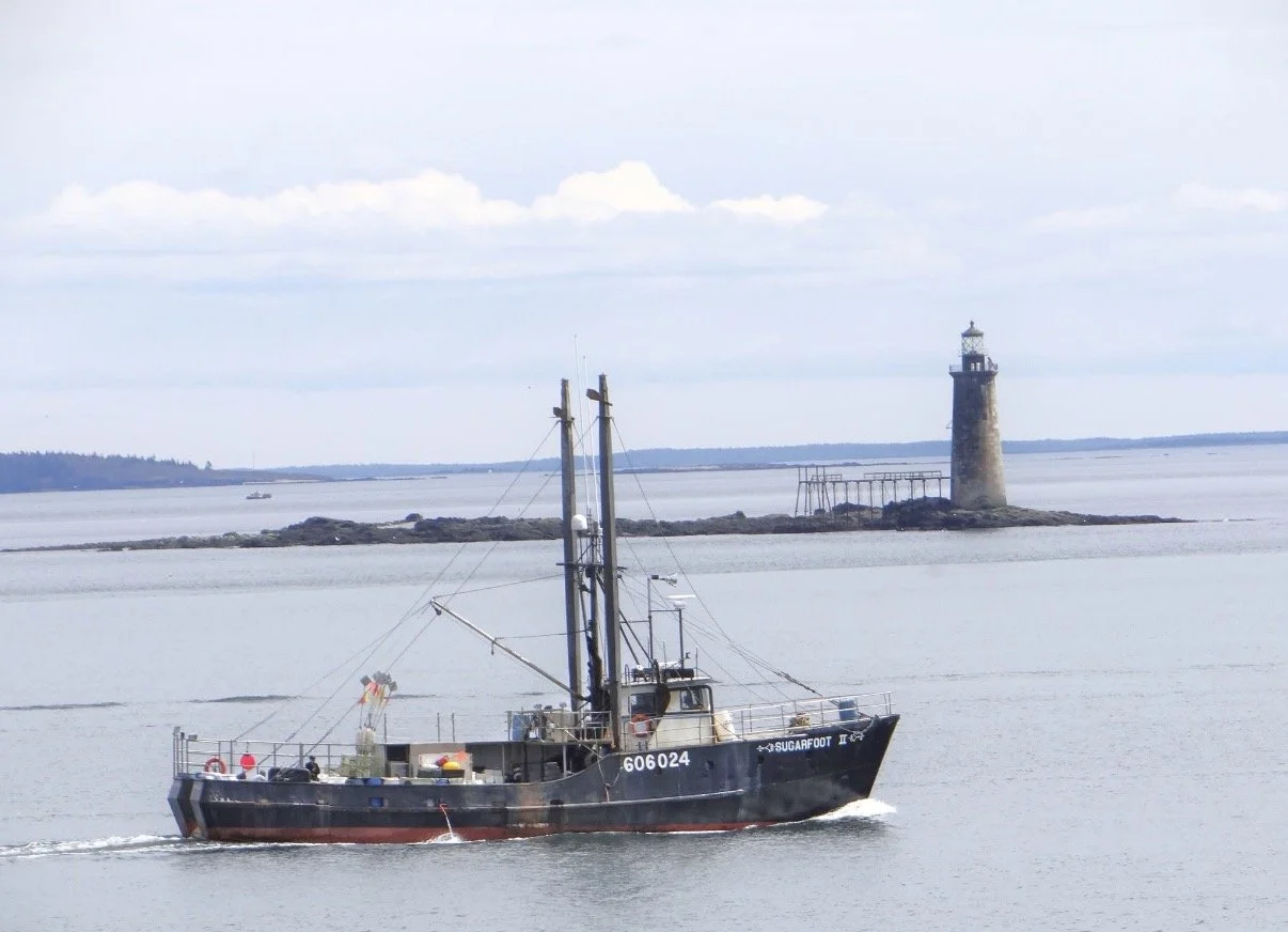 Fishing boat on calm water with a distant lighthouse.