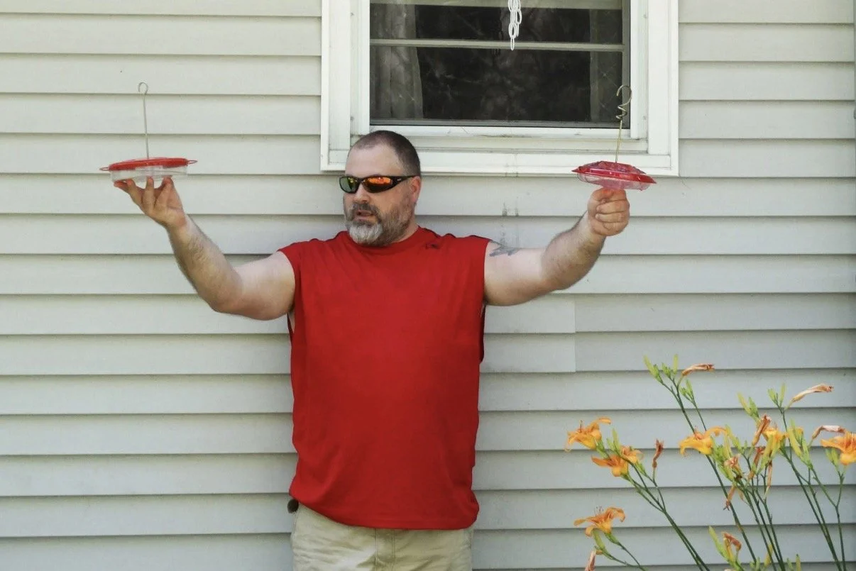 Person in a red sleeveless shirt holding small red objects in outstretched hands.