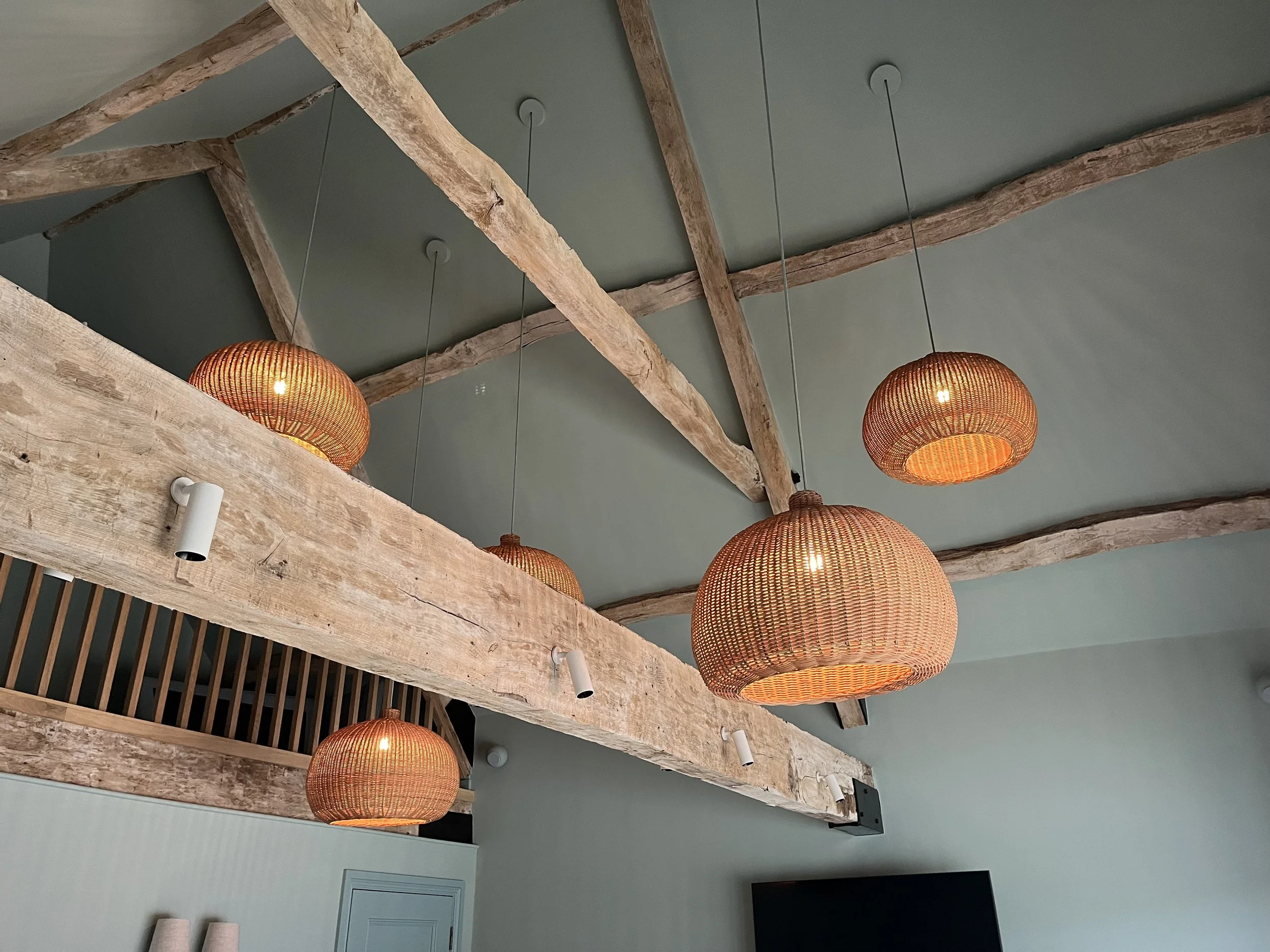Room with exposed wooden beams and multiple hanging woven pendant lights