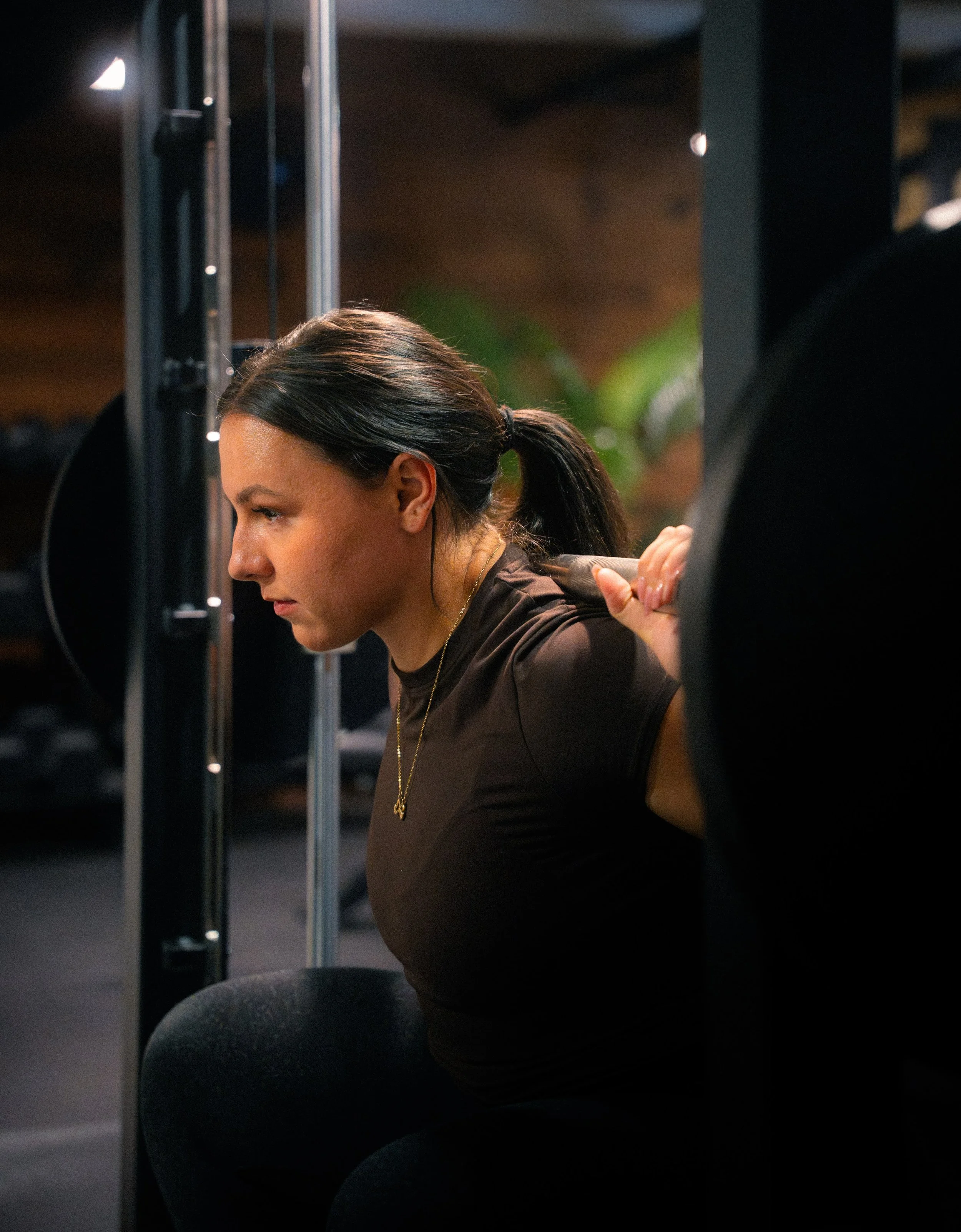 A woman is lifting a barbell during a workout at the gym.