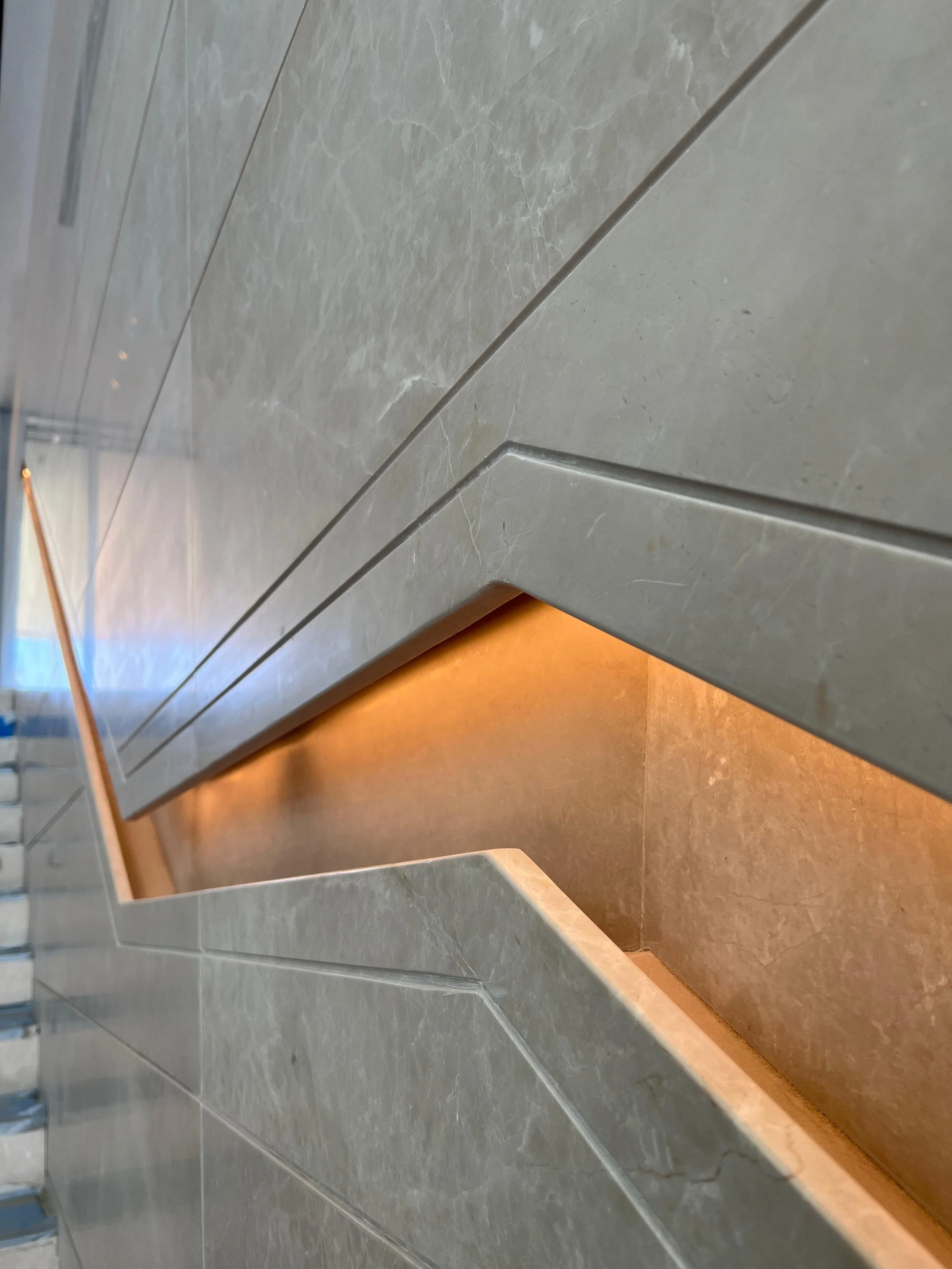 Close-up of a modern, beige marble fireplace with warm interior lighting.