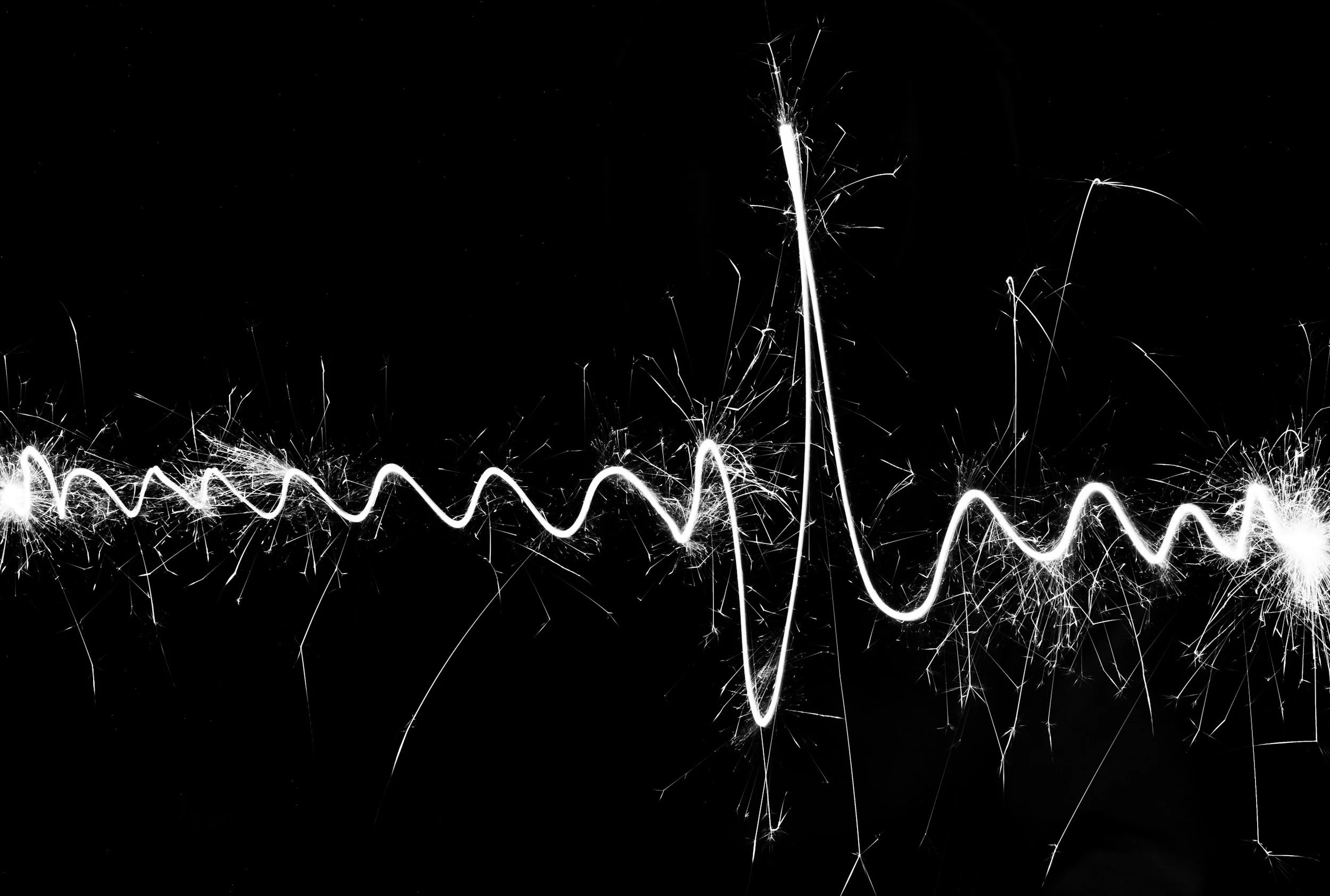Sparklers creating bright, zigzagging and spiral light trails against a black background.