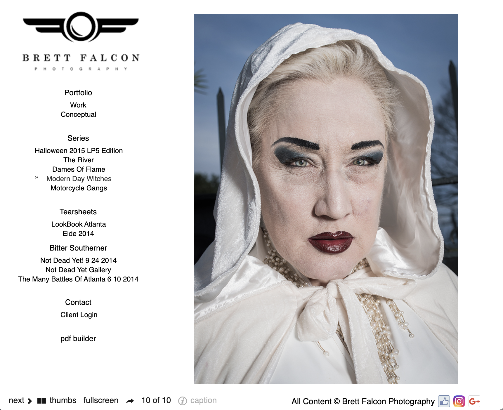 A close-up photograph of an older woman with platinum blonde hair, wearing dramatic dark makeup and a white hooded cloak, outdoors against a cloudy sky with trees in the background.