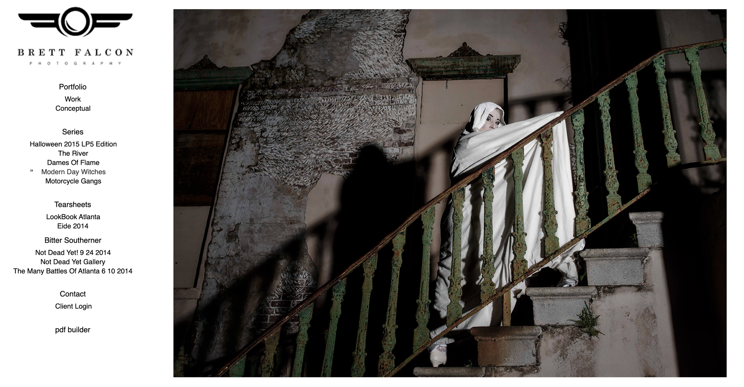 A person dressed as a ghost in a white sheet with eye holes, standing on an old concrete staircase with a rusted green metal railing, inside a building with damaged walls and peeling paint.
