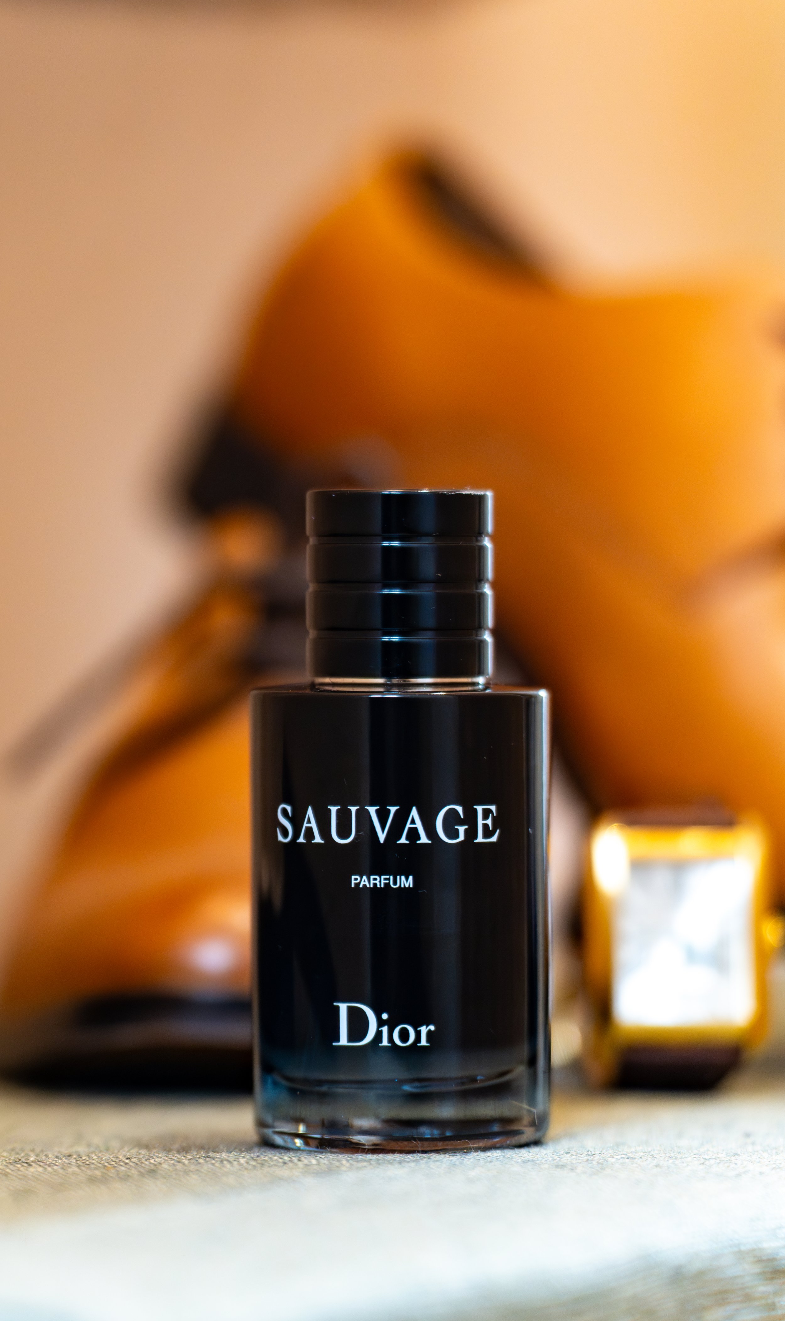 Flacon de parfum Dior Sauvage en premier plan avec d'autres flacons flous en arrière-plan.