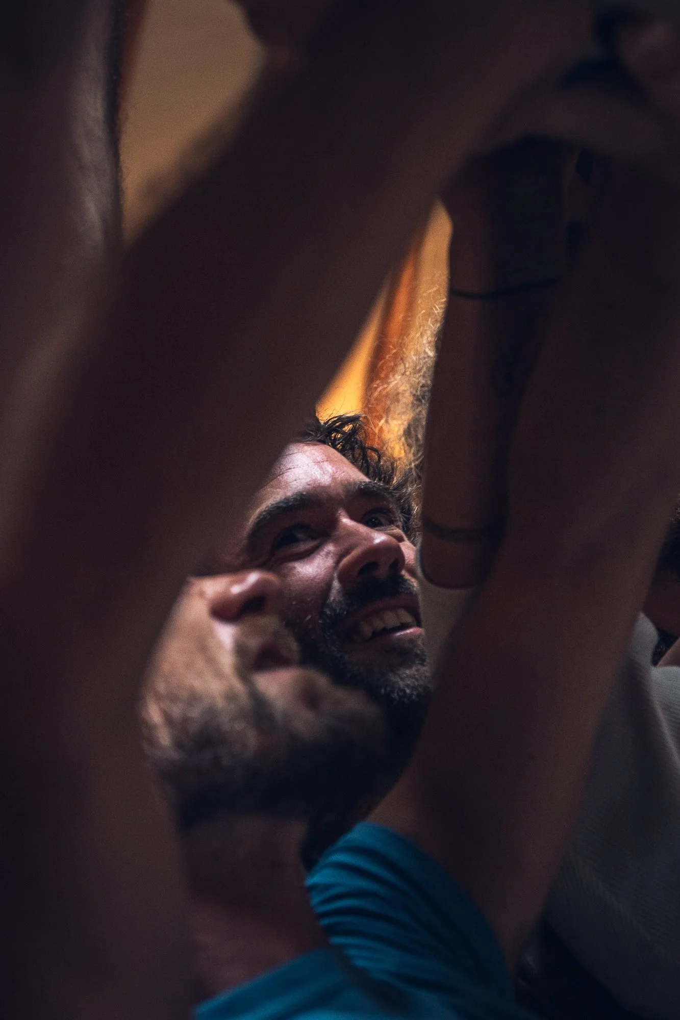 Two men sharing an intimate moment, with one man smiling and looking up, partially obscured by an arm and the other person's body.