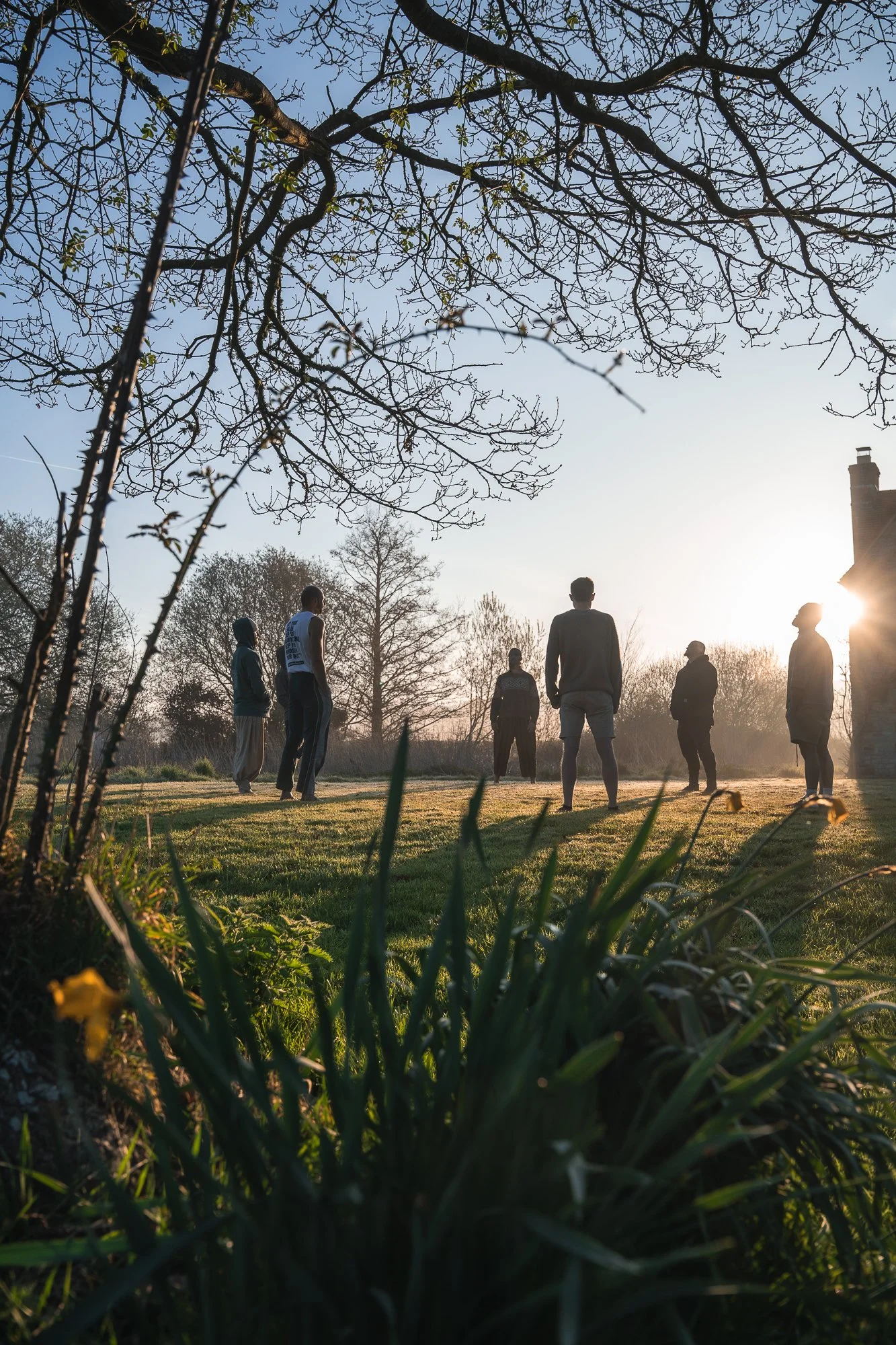 Men standing in a circle outdoors at sunset