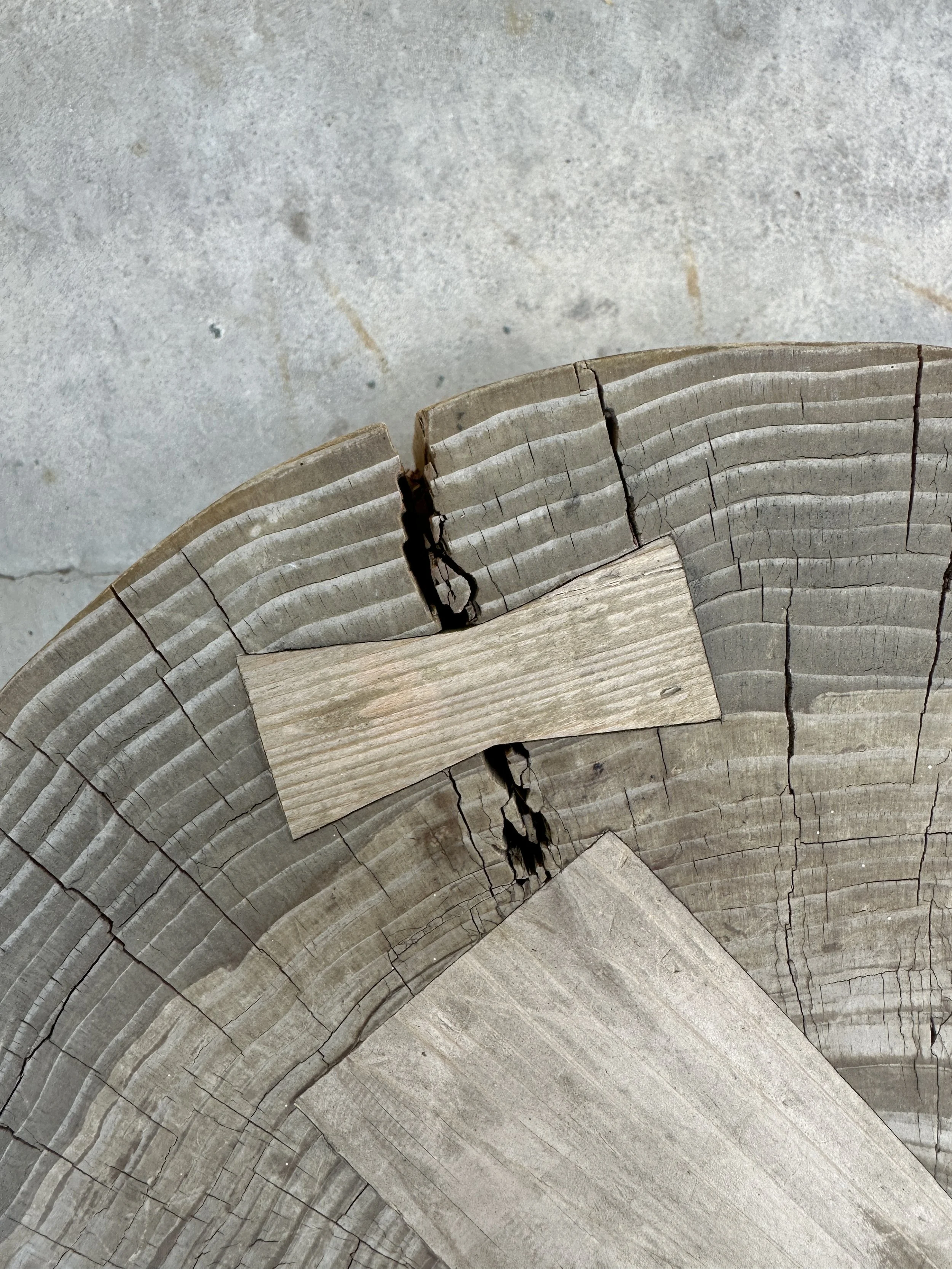 Close-up of cracked and damaged wooden beams on a concrete floor.