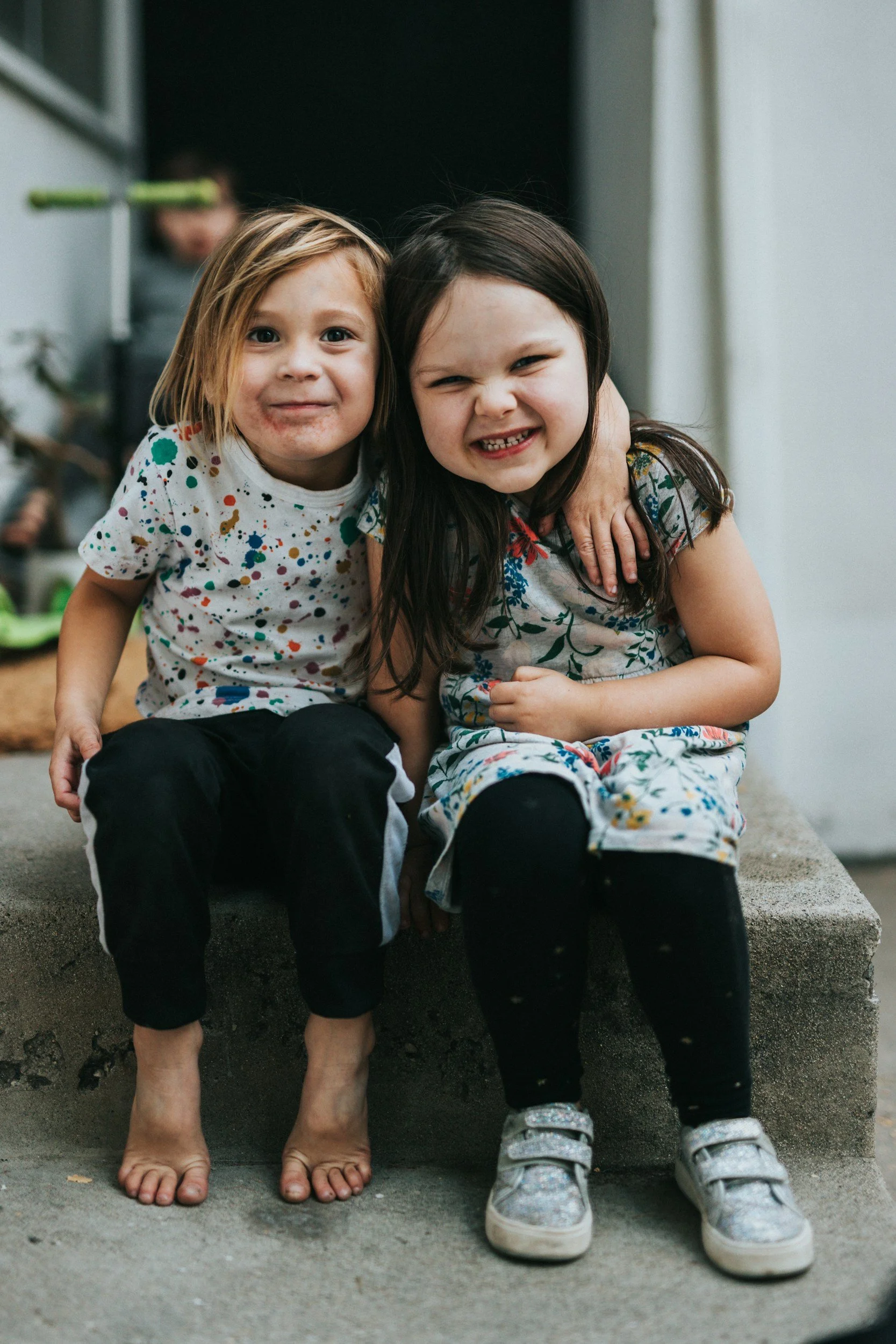 Two young kids with arm around each other smiling.