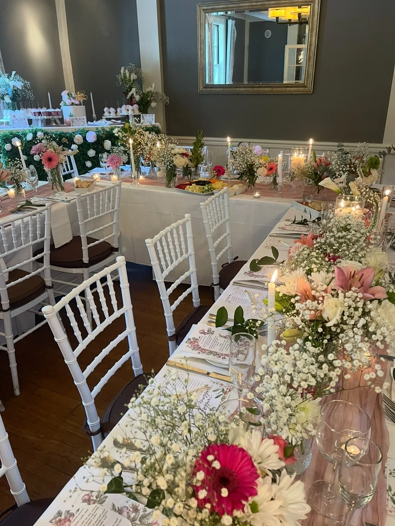 Set dining table decorated with flower arrangements, candles, wine glasses, and printed menus for a special event or celebration. Wedding & Event Planner Hudson Valley, NYC, New York, Bergen County, New Jersey