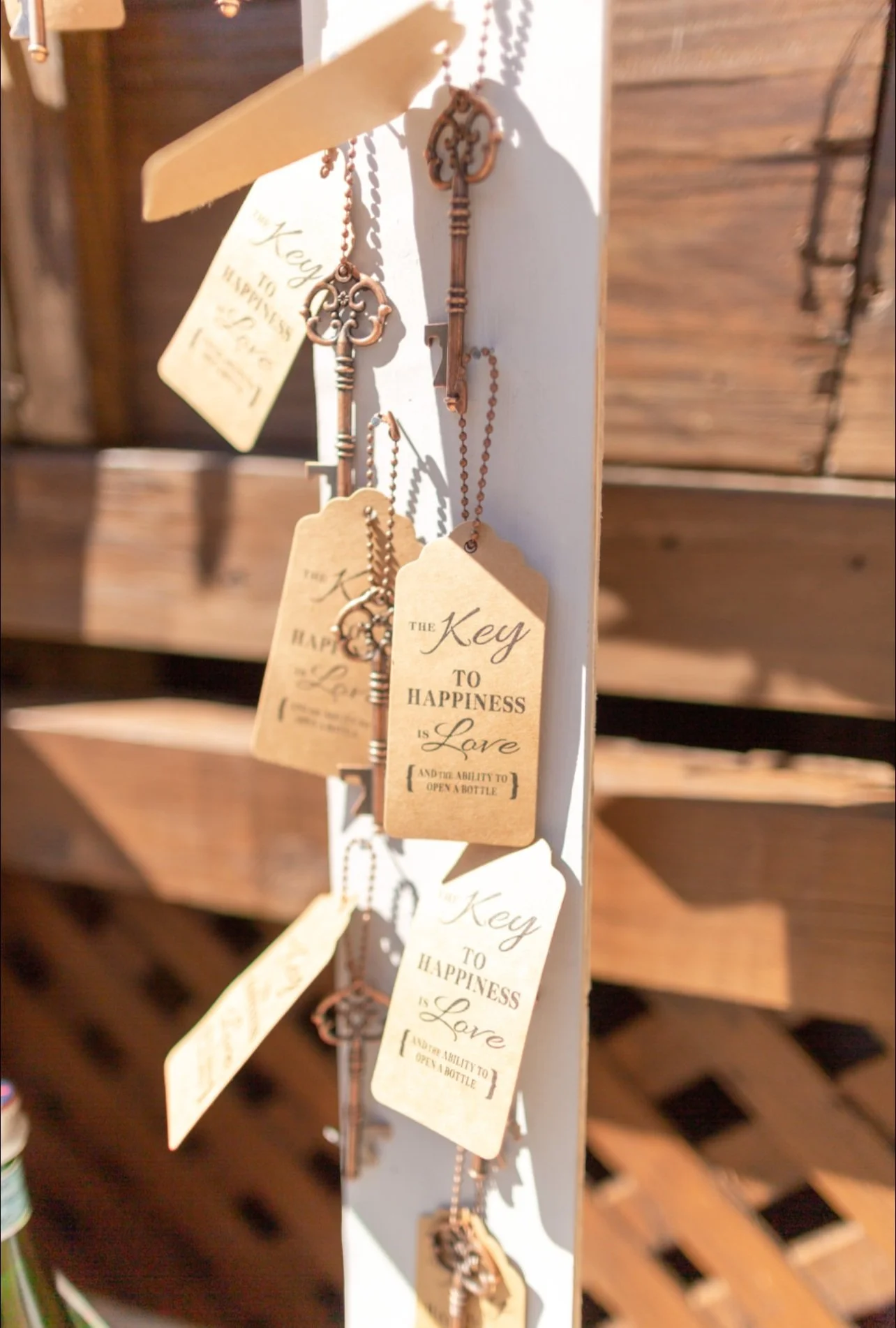 Keys hanging on a display board with tags that read 'The key to happiness is love and the ability to open a bottle.'