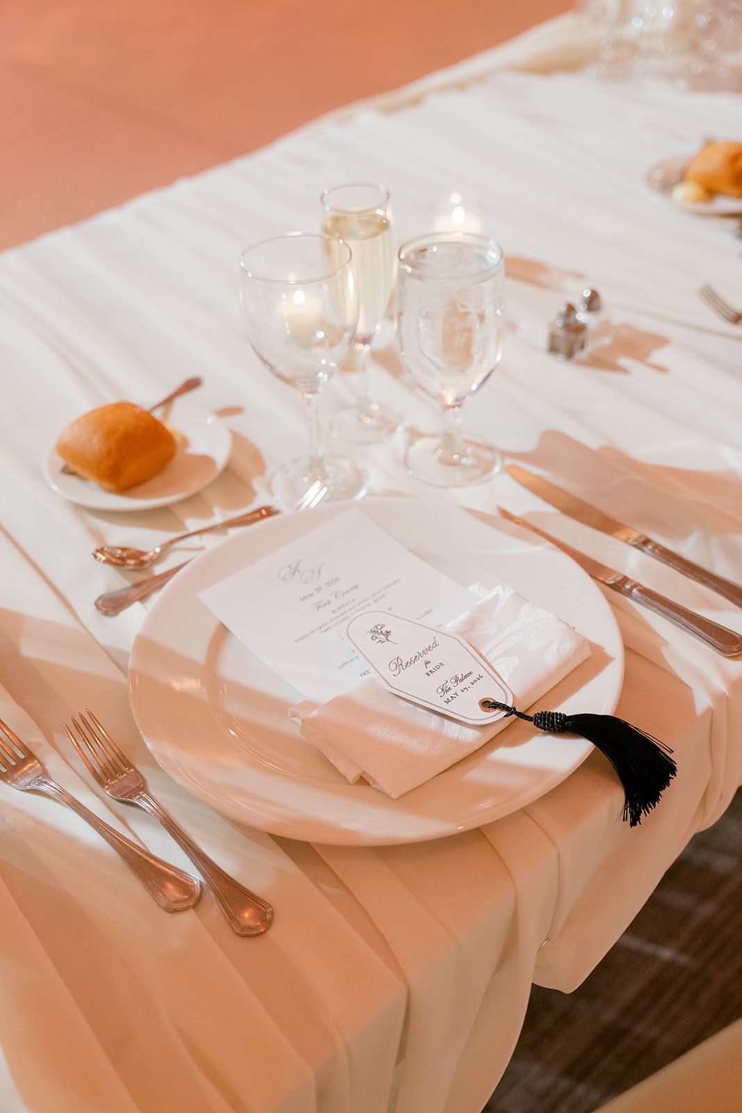 Textured linen, glassware, candlelight, and flowers on a reception table