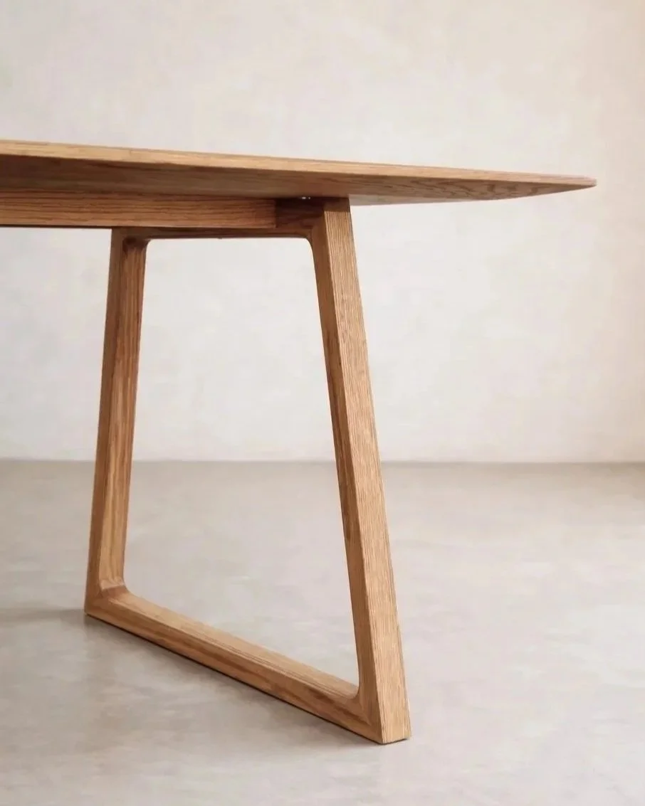 Detalle del alero de la encimera de mesa de comedor en madera maciza de roble. Patas trapezoidales y diseño minimalista.