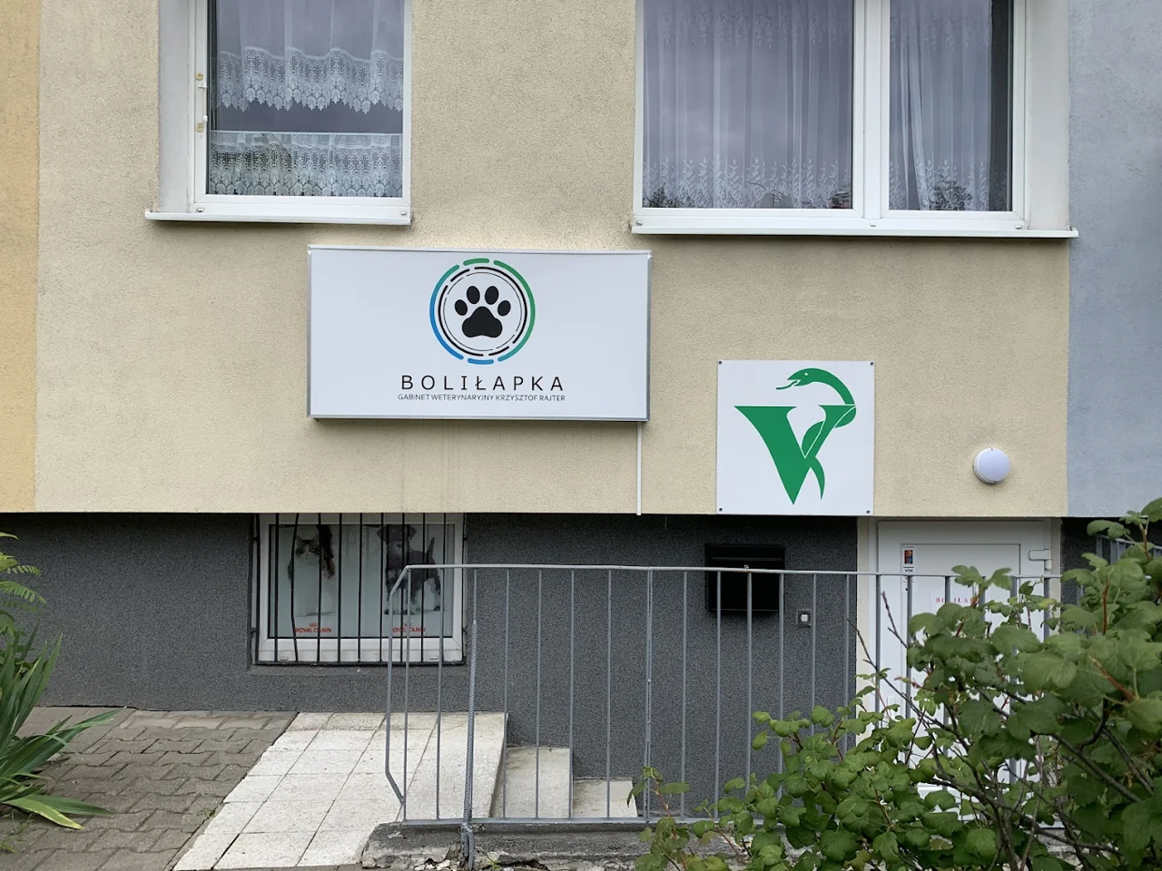 Znak na zewnątrz budynku z logo przedstawiającym odcisk łapy i napisem „BOLIŁAPKA GABINET WETERYNARYJNY KRZYSZTOF RAJTER”