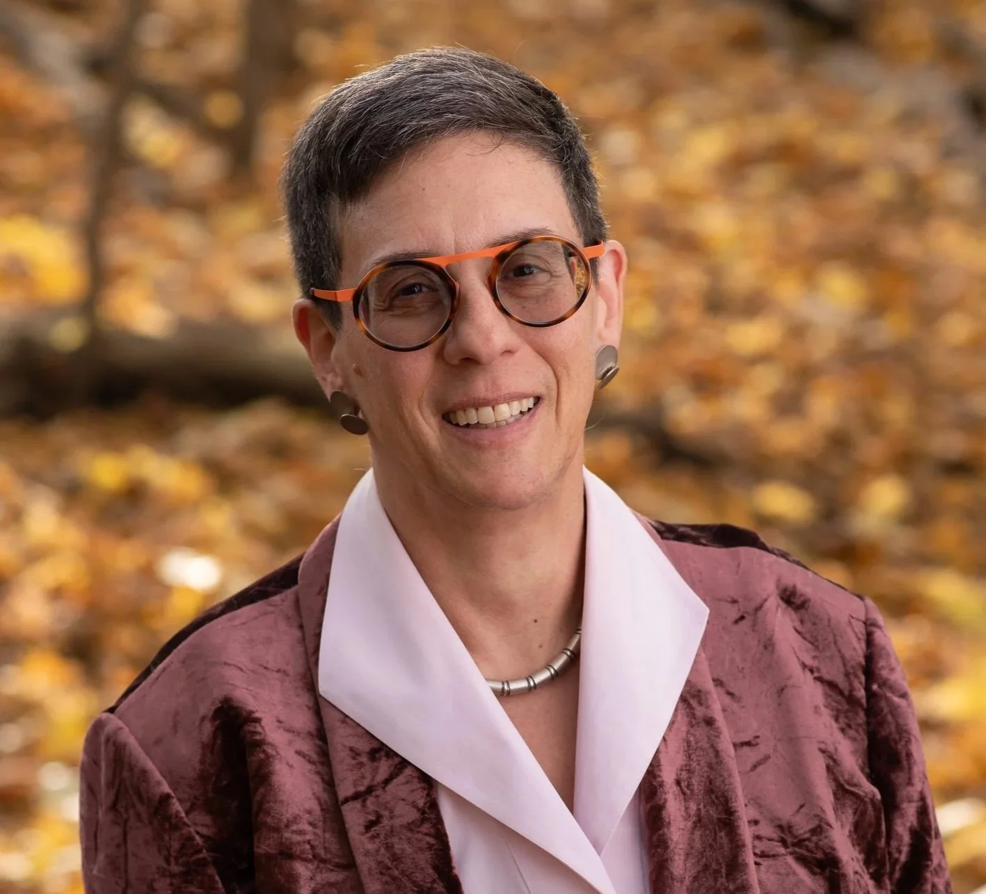 Professional portrait of Robin smiling outdoors.