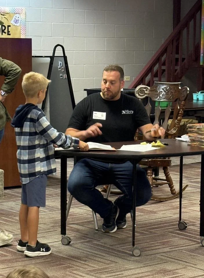 AB Wade signs a book for child a an elementary school